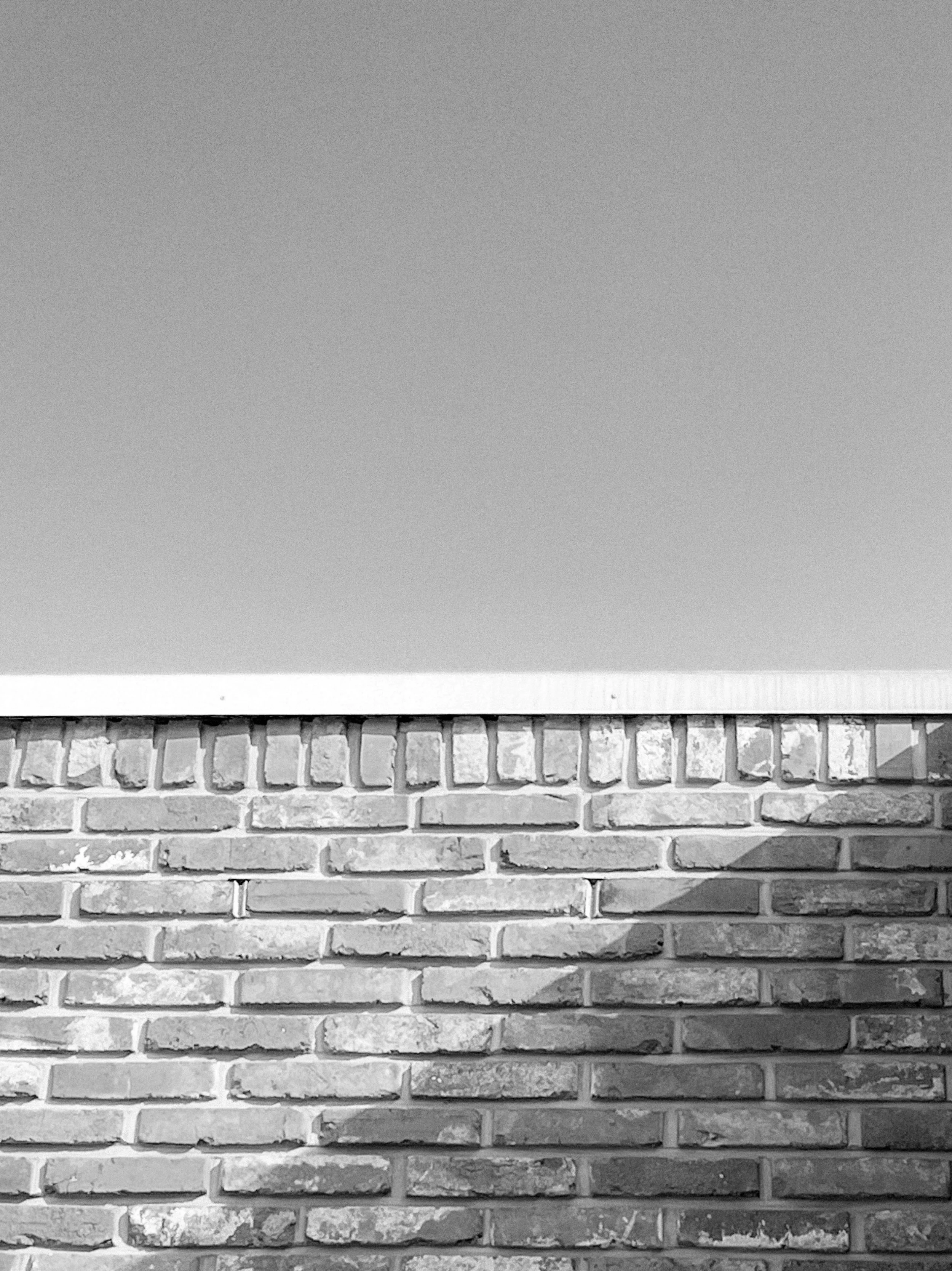 Black and white photo of a brick wall with space above for sky or other background.