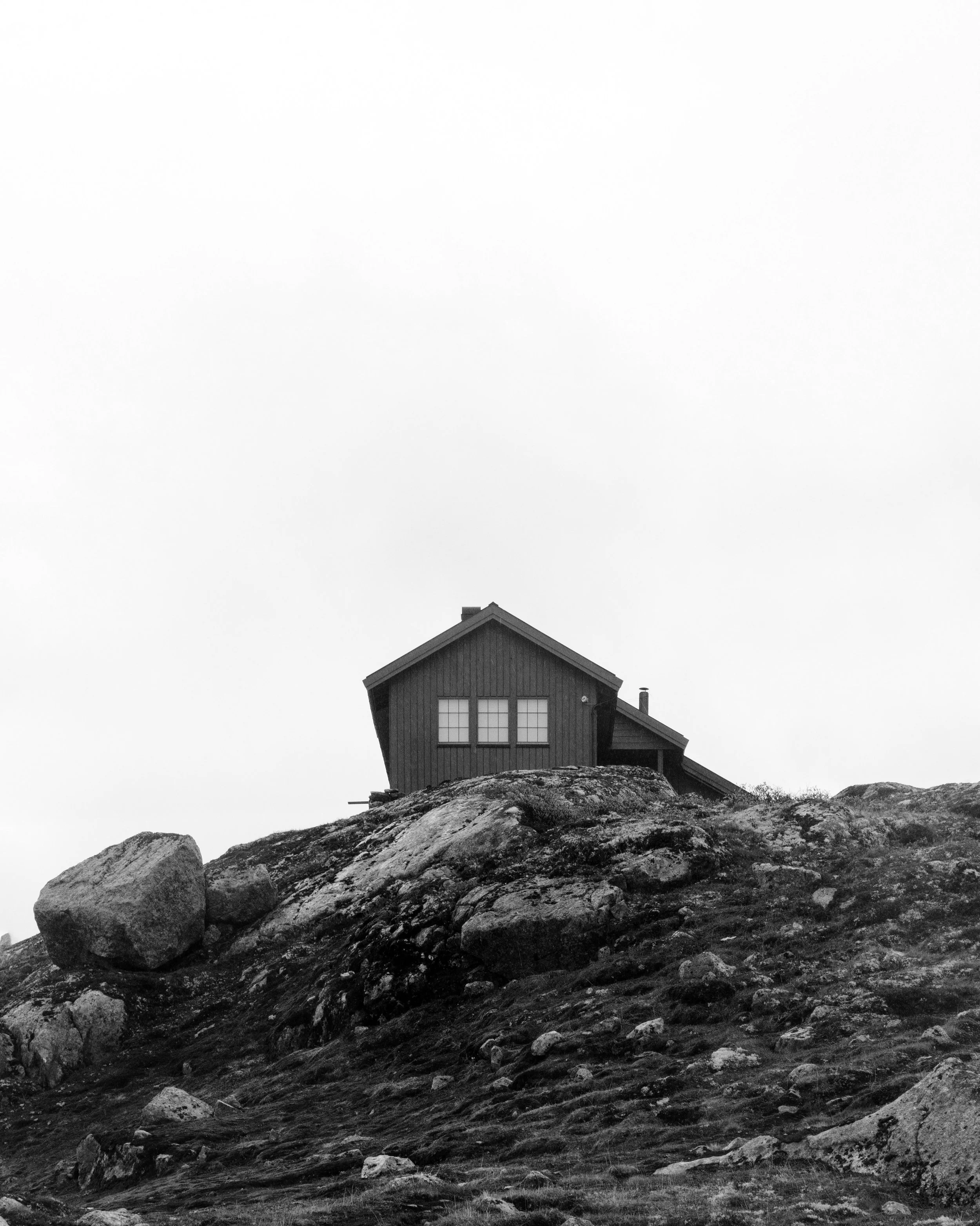 A small house on a rocky hillside, black and white photo.