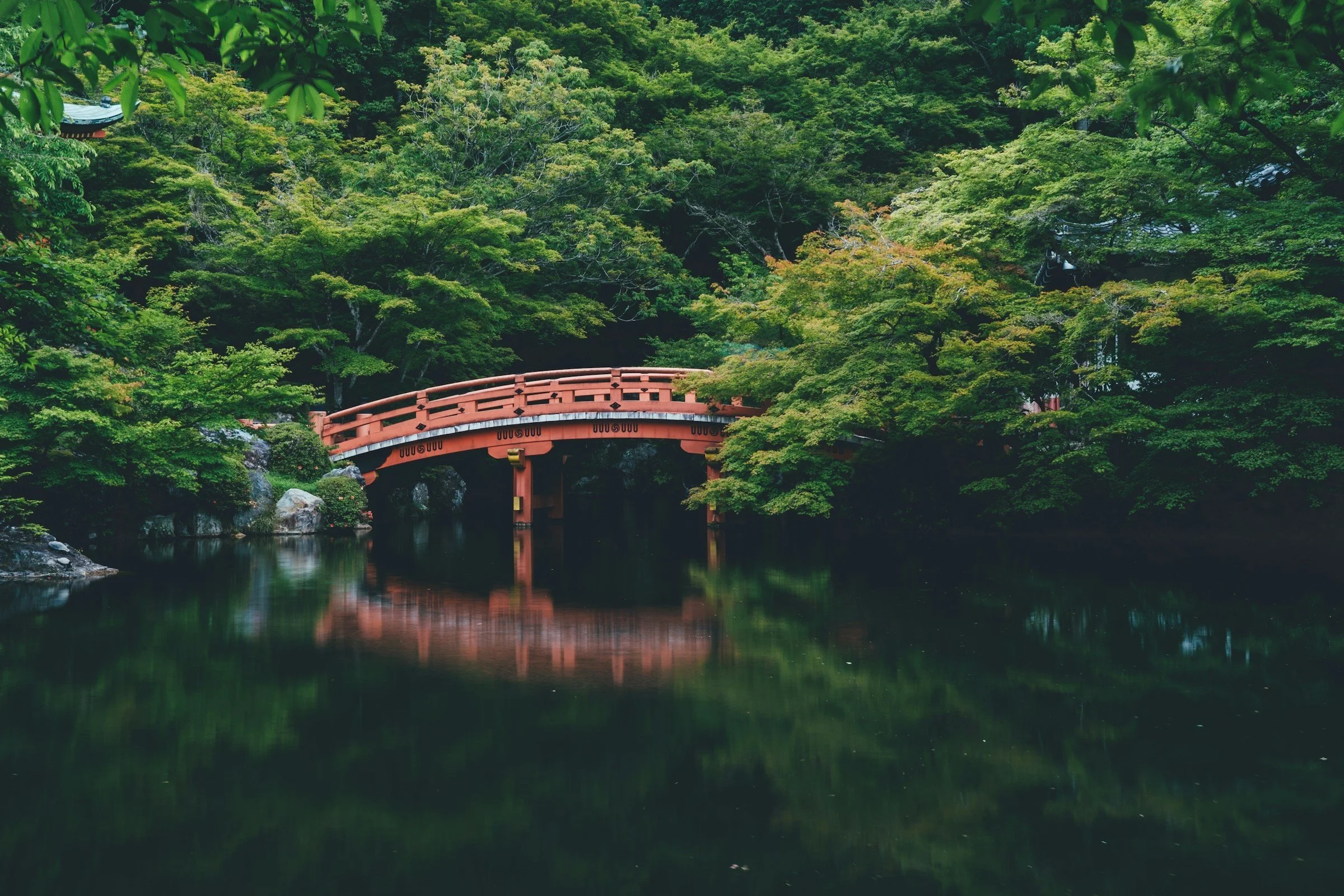 A red Japanese bridge over a still pond
