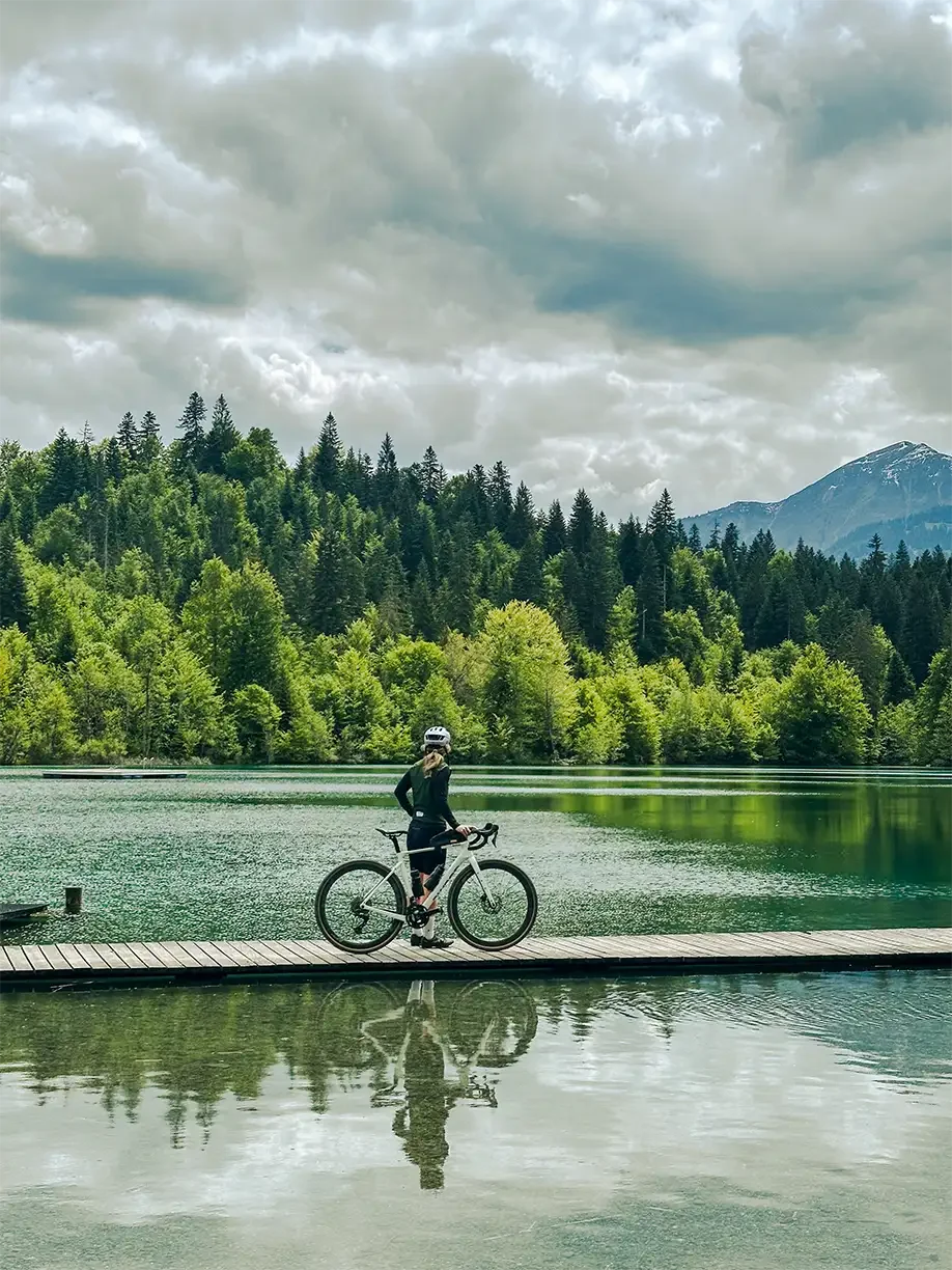 Radfahrerin auf einem Steg, blickt in die Ferne und hält ein Awson Fahrrad