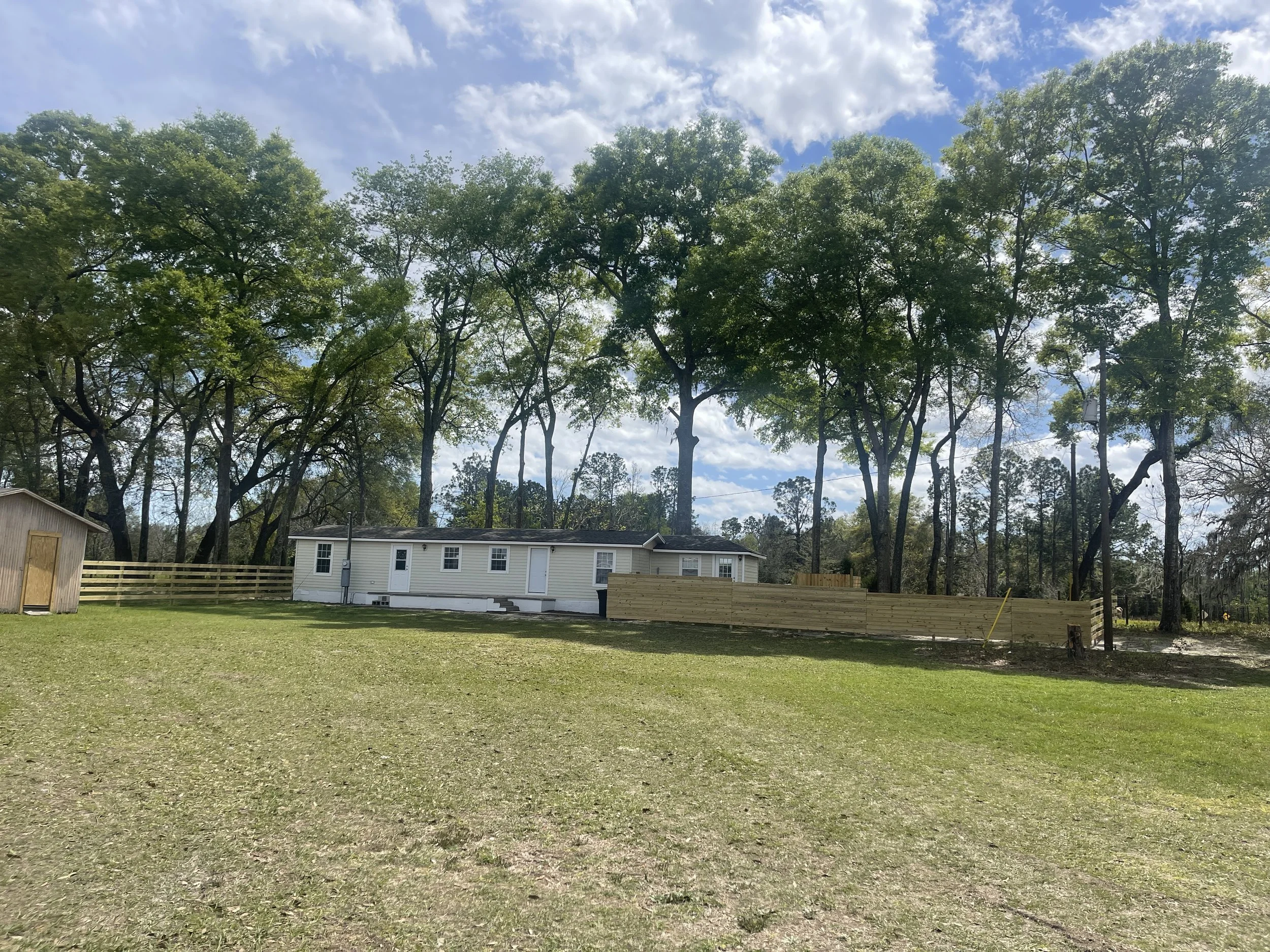 Exterior view of the studio rental featuring a private fenced-in entrance for added seclusion, surrounded by sprawling green country land and open skies.