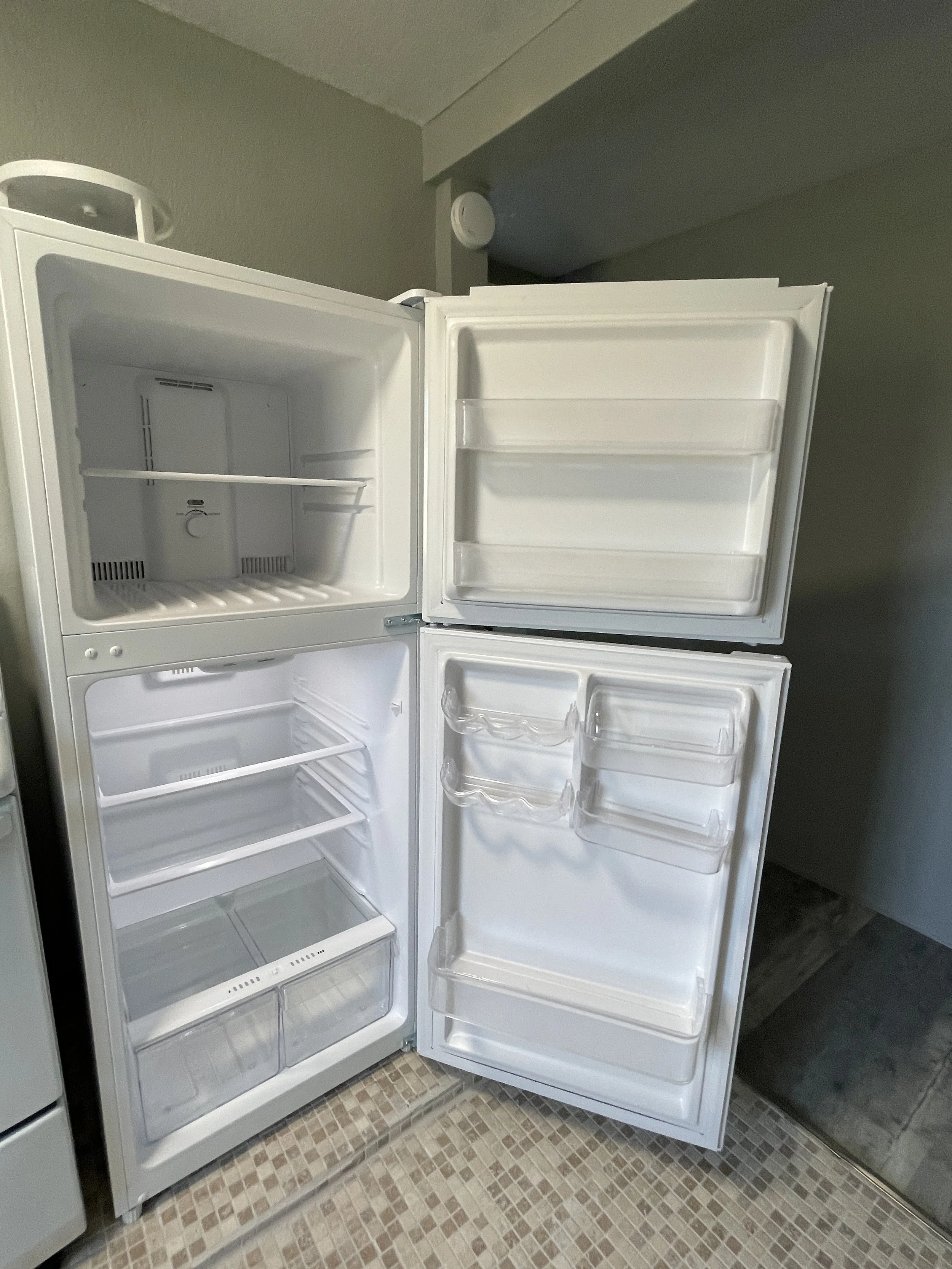 Clean and spacious refrigerator interior for a studio rental, showing open doors, organized shelving, and ample storage for groceries.