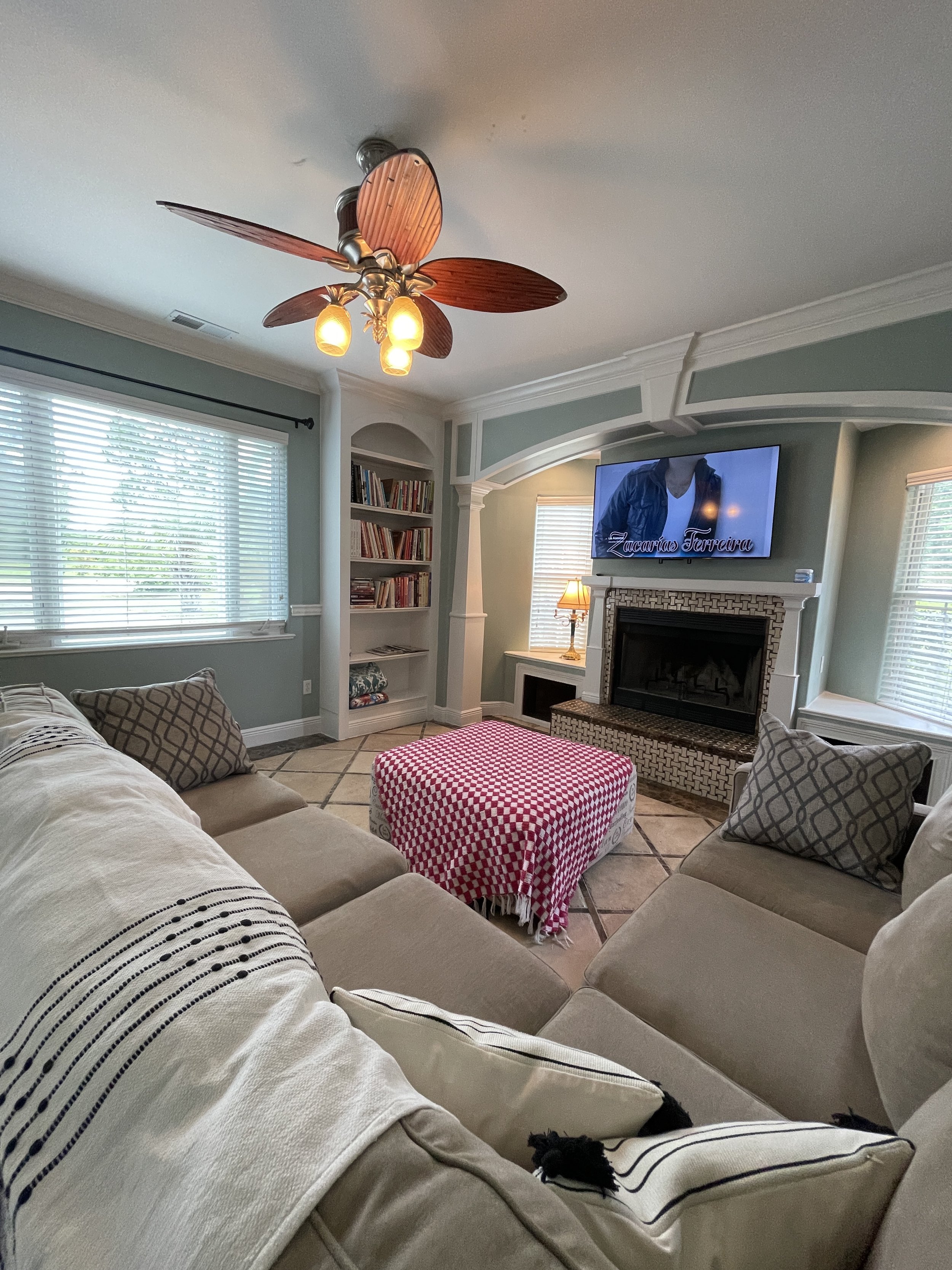 Cozy living room with a wood-burning fireplace, custom built-in bookshelves, and a modern L-shaped sectional couch.
