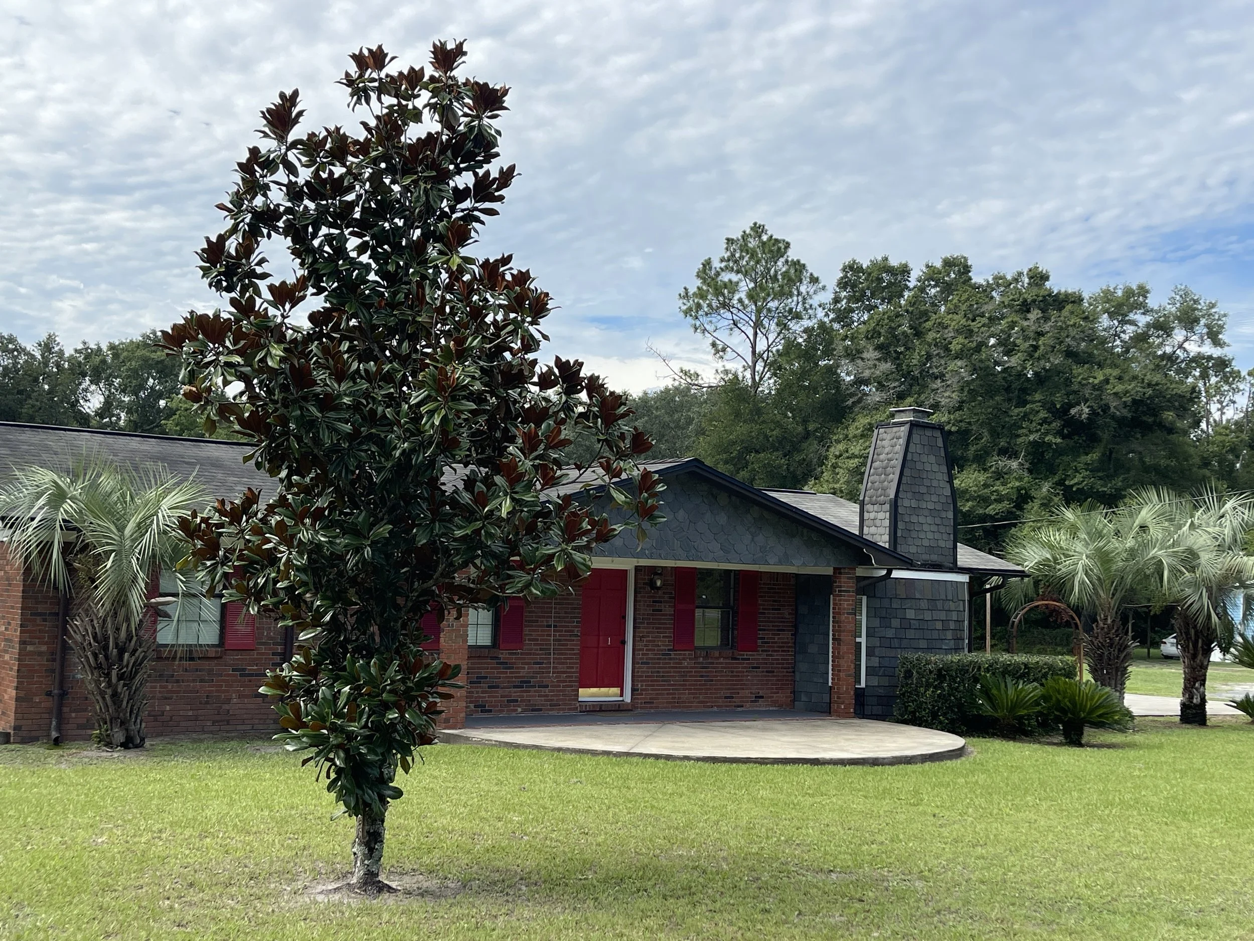 Exterior view of a charming red brick Airbnb home, conveniently located just five minutes from I-75, featuring a large driveway and classic architecture—an ideal overnight stopping point for highway travelers.