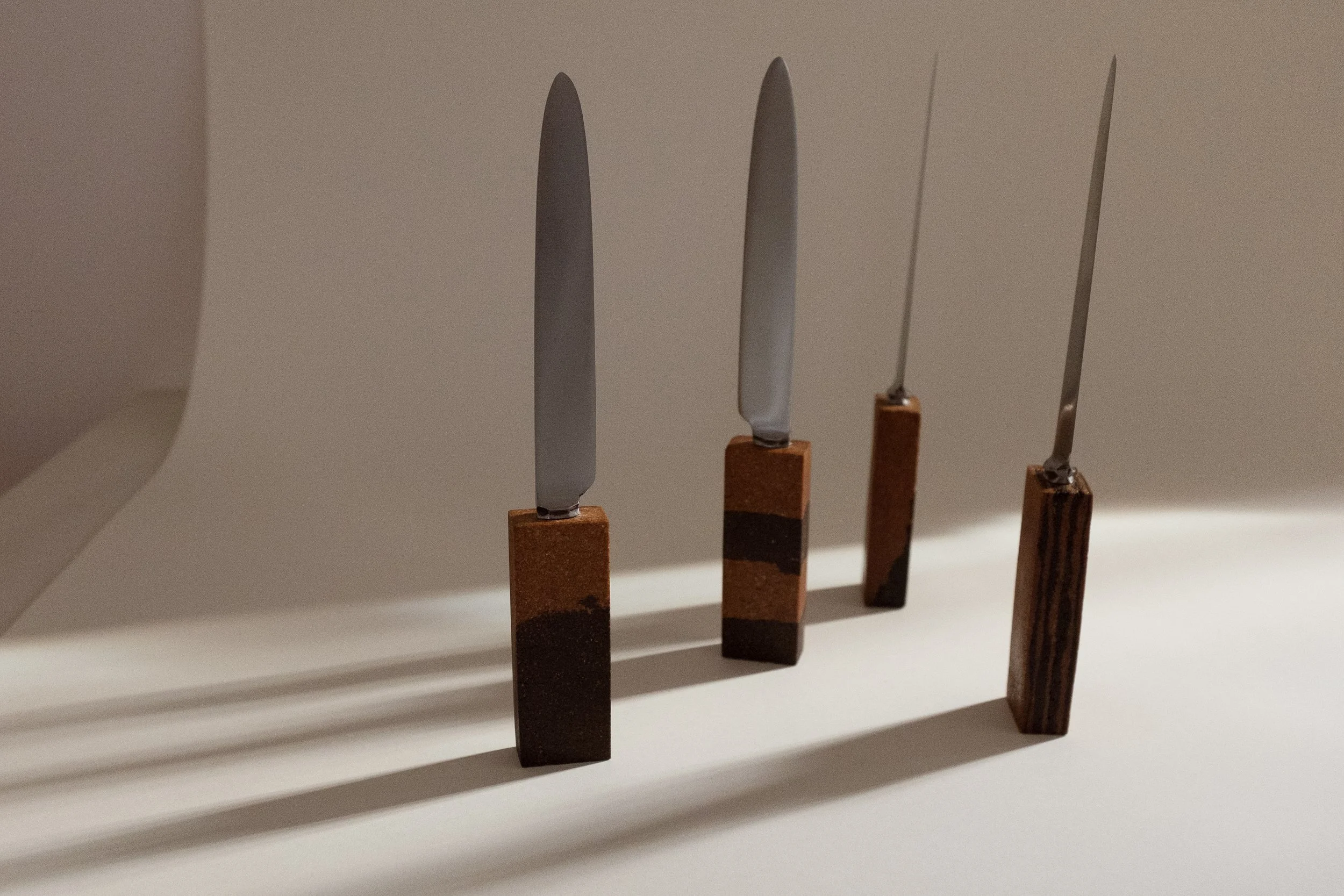Knives with earthy toned handles in front of white background