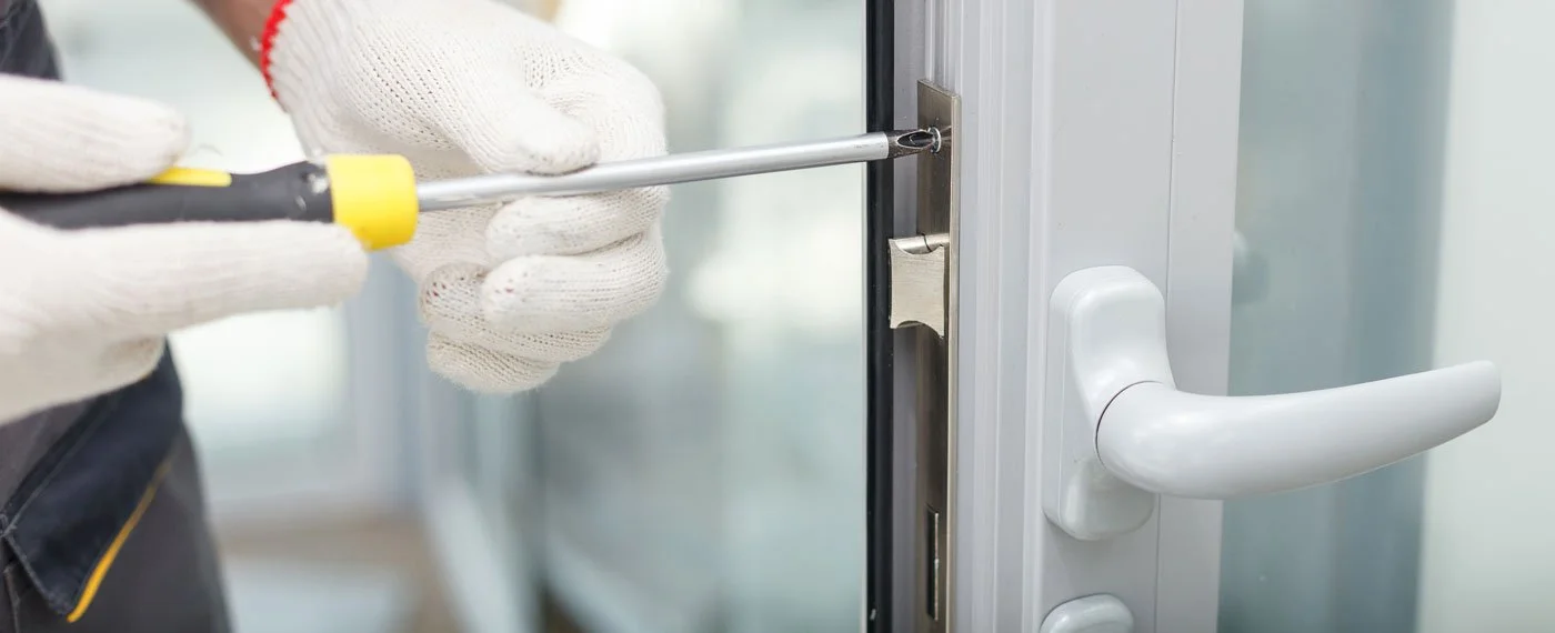 Una persona con guanti sta usando un cacciavite per installare o riparare la maniglia di una porta.