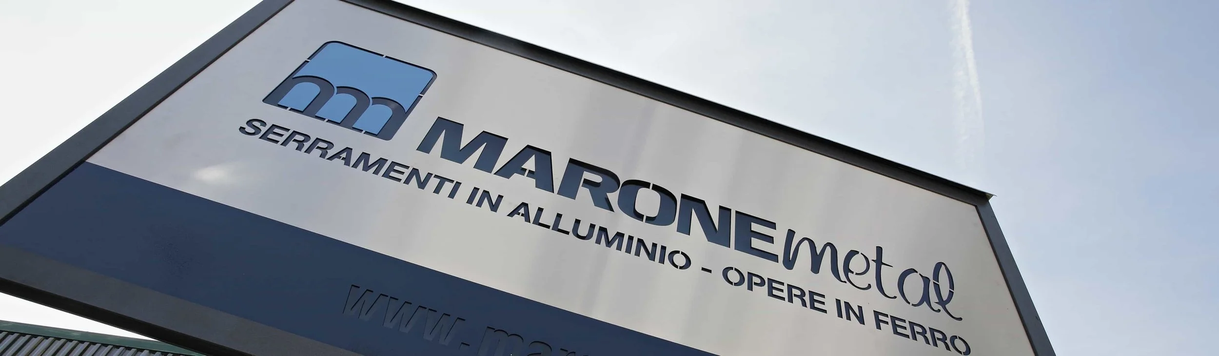Cartello aziendale con logo e testo di MAFREON METAL, specializzata in serramenti in alluminio e opere in ferro.
