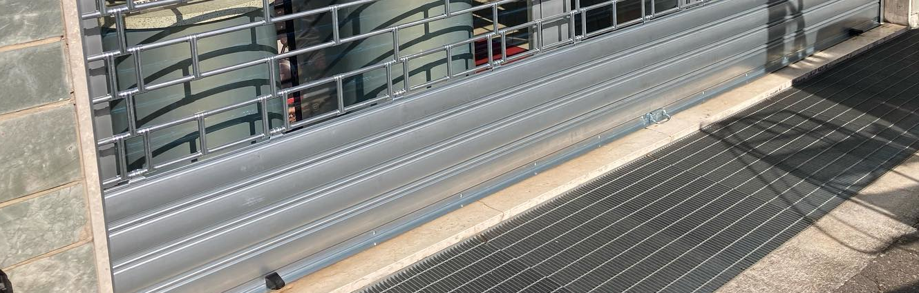 Scarpaltrasniera metallica in posizione abbassata davanti a una serranda metallica