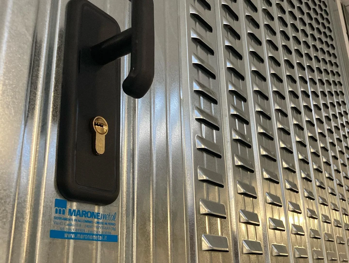 Vano di accesso con serratura e maniglia in metallo su un pavimento di lamiera zincata con grate di aerazione.