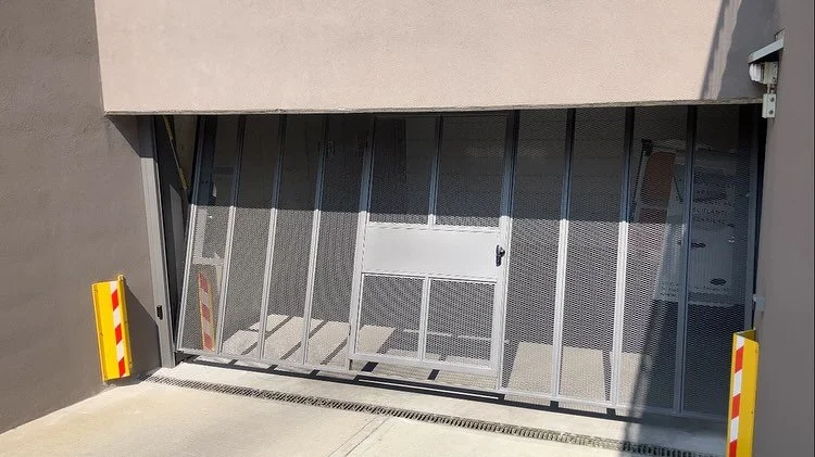 porta automatica di un garage con struttura in metallo e protezioni laterali colorate