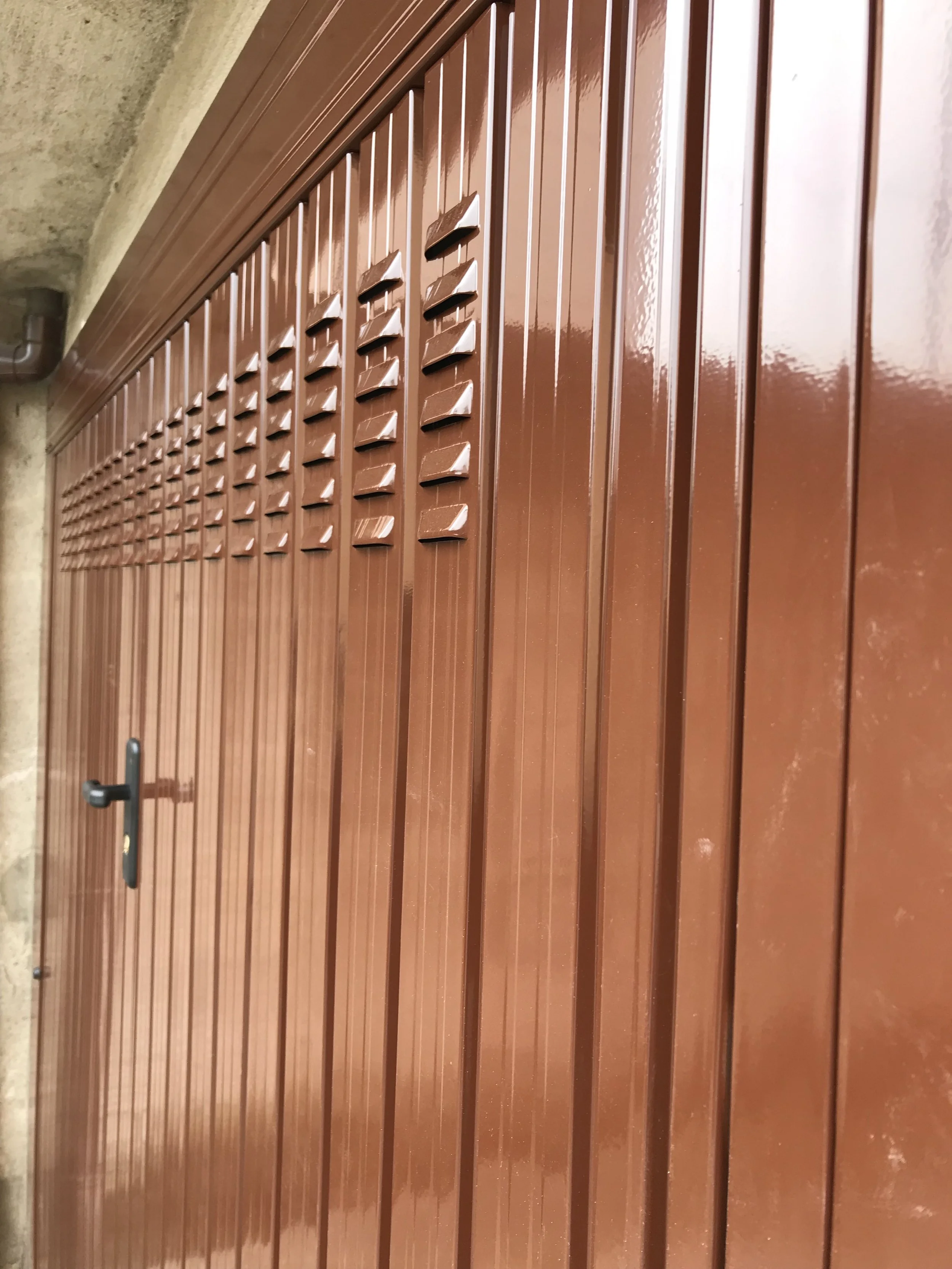 Porte di un garage in metallo di colore marrone con serrature e gratelle di aerazione sulla parte superiore.