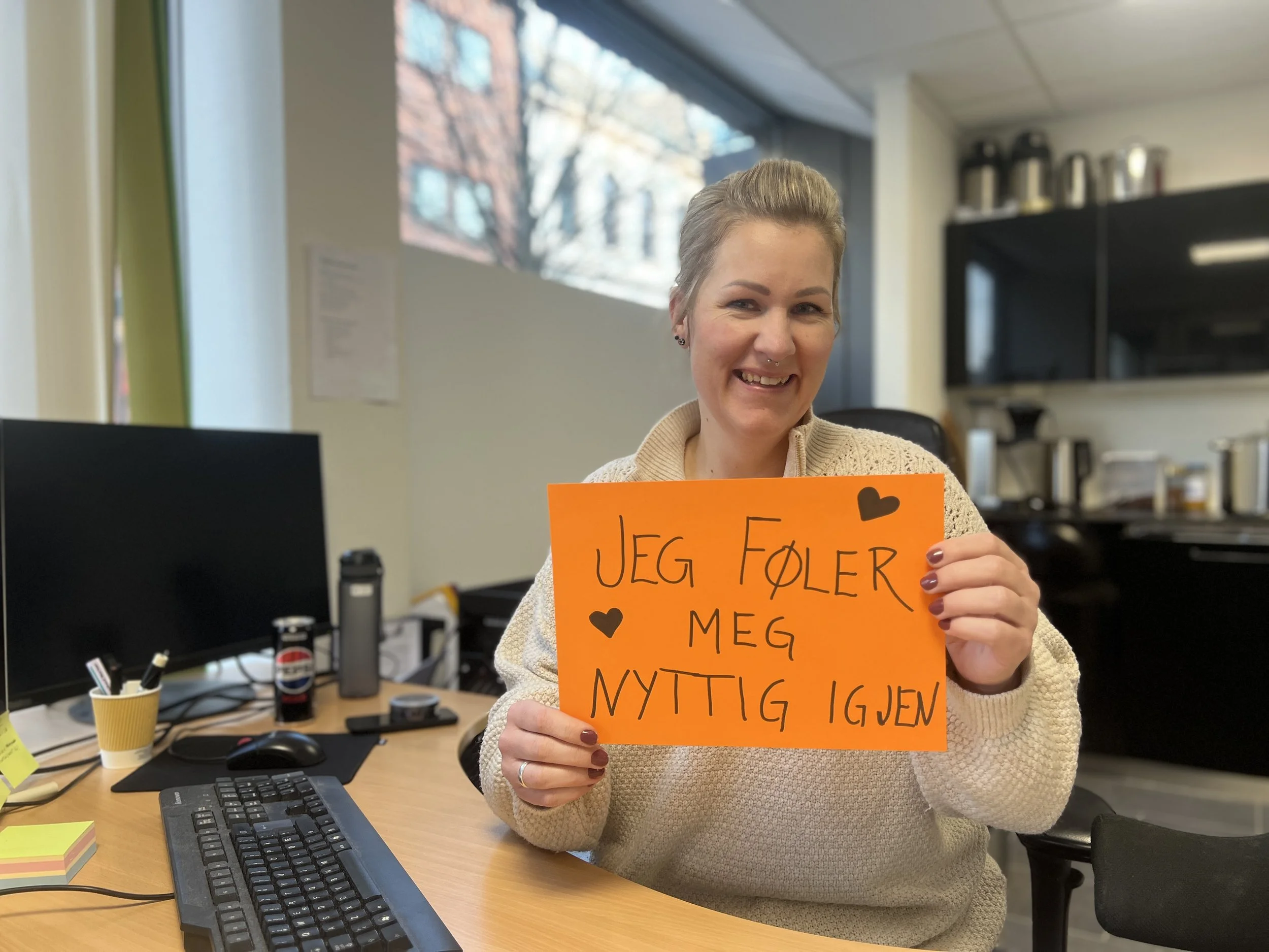 Medlem som holder opp en plakat som sier "Jeg føler meg nyttig igjen"