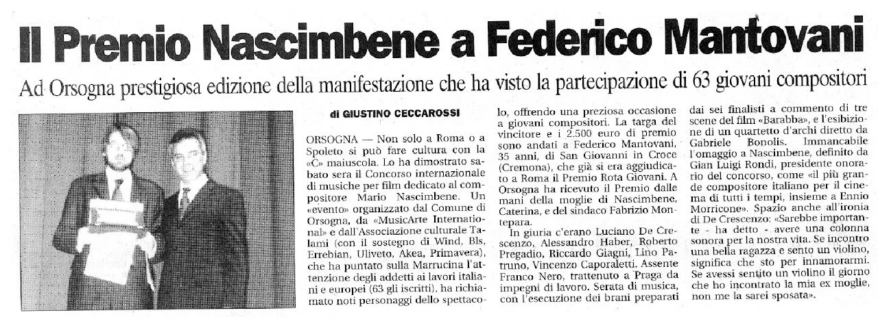 Due uomini in giacca e cravatta in piedi, uno di fronte all'altro, in un evento di premiazione musicale.