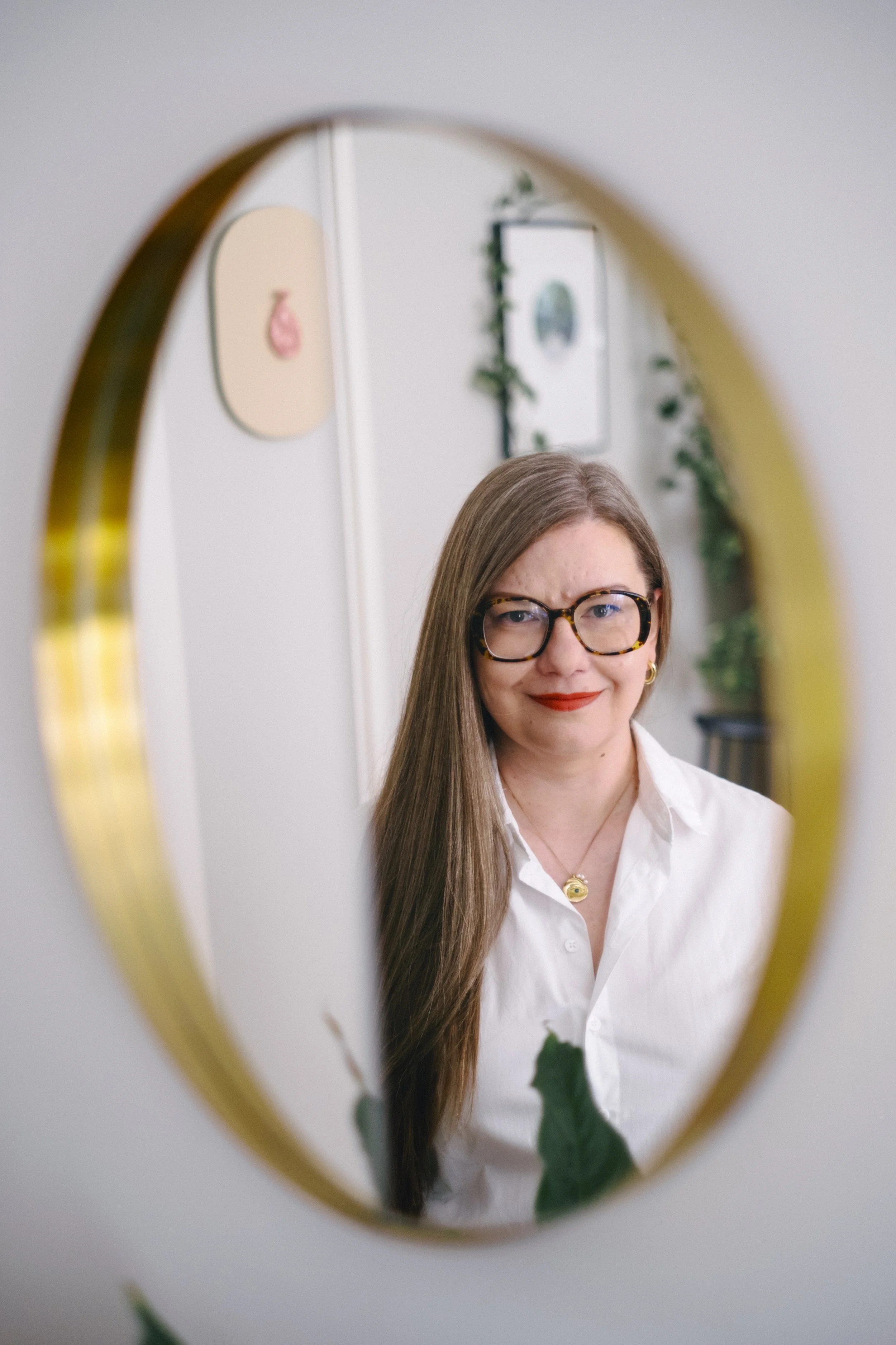 Hanna Kuokka katsoo itseään koristeellisesta peilistä. Taustalla taidetta.