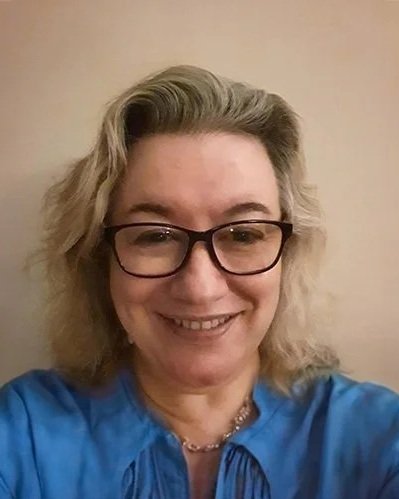 Laura Spalvieri- principle psychotherapist-the life studio- smiling in front of a beige wall. Registered clinical therapist, hypnosis, trauma, depression.