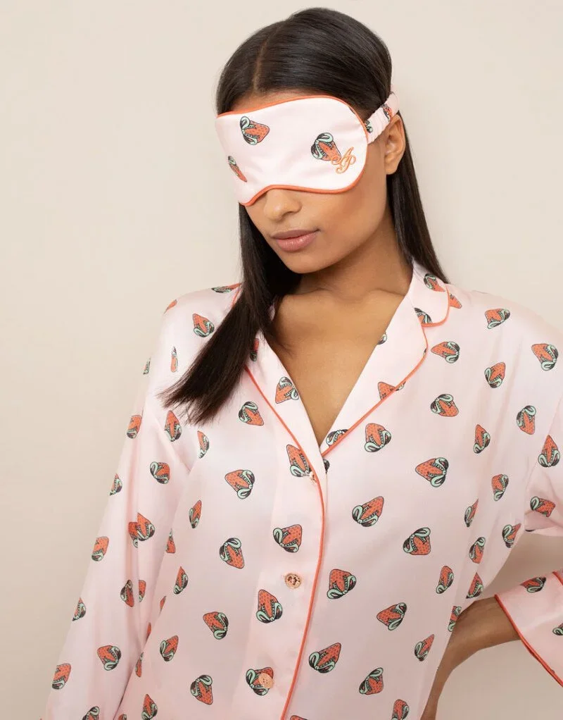 Woman wearing matching pajama top and sleep mask with a sushi pattern.