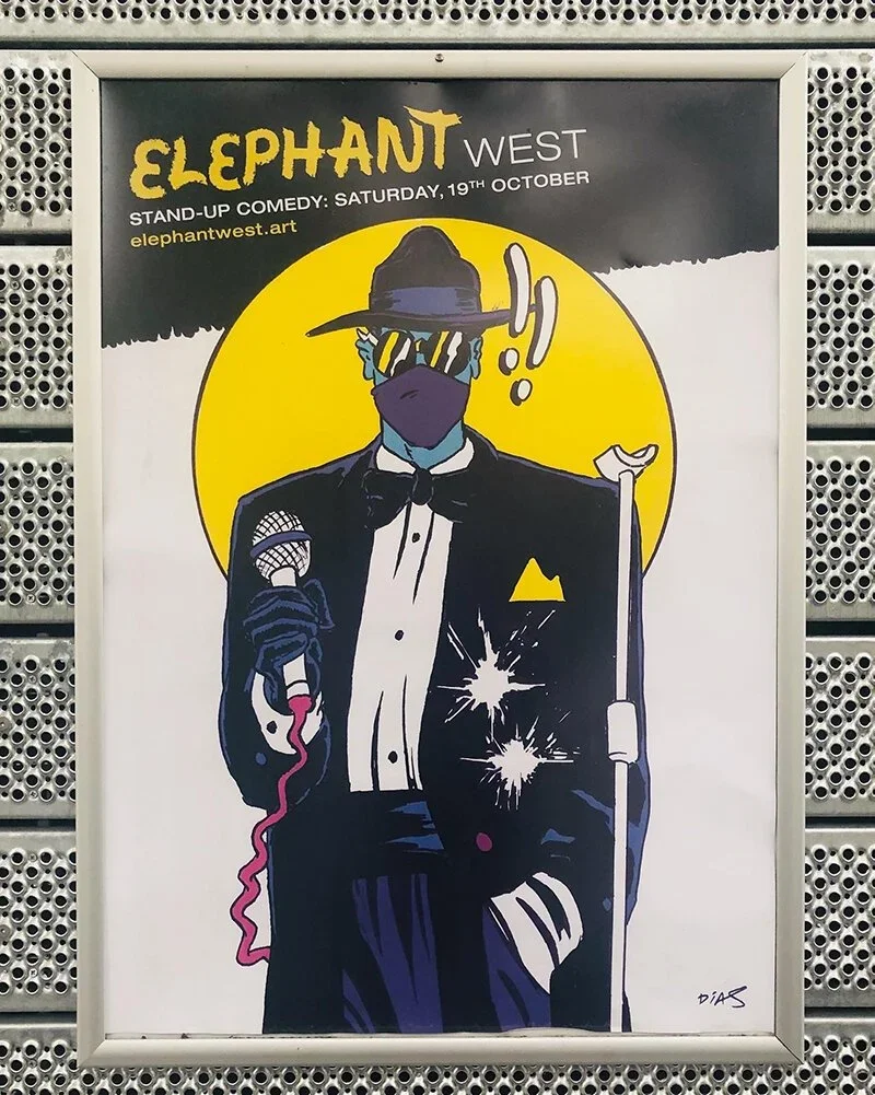A poster for Elephant West comedy show featuring a stylized illustration of a man dressed as a gangster with a fedora, sunglasses, and bow tie, holding a microphone and a cane, with a yellow circle background, and event details at the top.