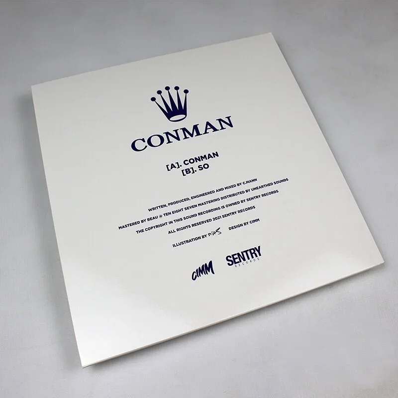 A white sheet of paper with text and logos, featuring a blue crown icon at the top, titled "CONMAN," with two pronunciation guides and additional information about the content below.