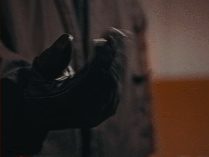 Person wearing black gloves holding a small object.