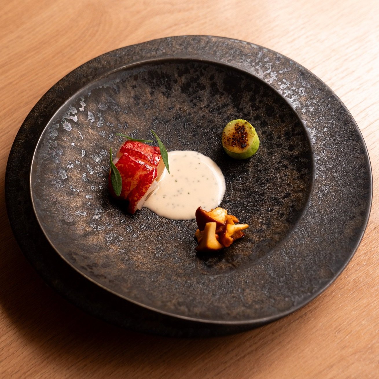 Charcoal-grilled Scottish blue lobster served with seasonal girolles, teriyaki sauce, trombetta courgette, and kinome dengaku at TAKU.