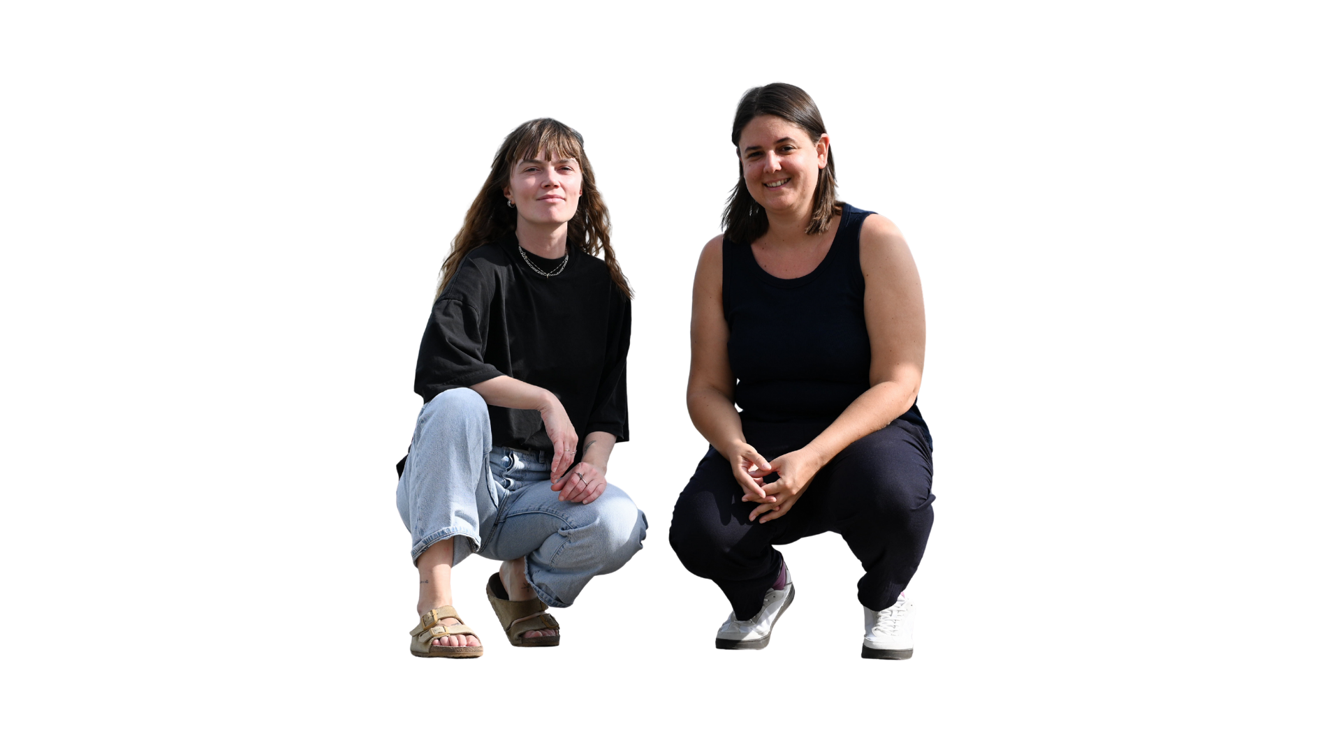 Zwei junge Frauen sitzen nebeneinander, lächeln und blicken in die Kamera.