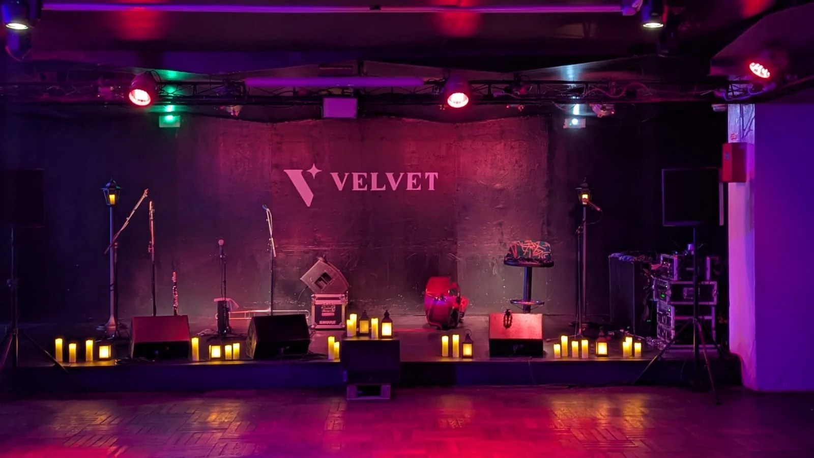 Scène de scène de stand-up ou concert dans une salle appelée Velvet, avec des microphones, un siège, un ukulélé, des candélabres et des éclairages colorés