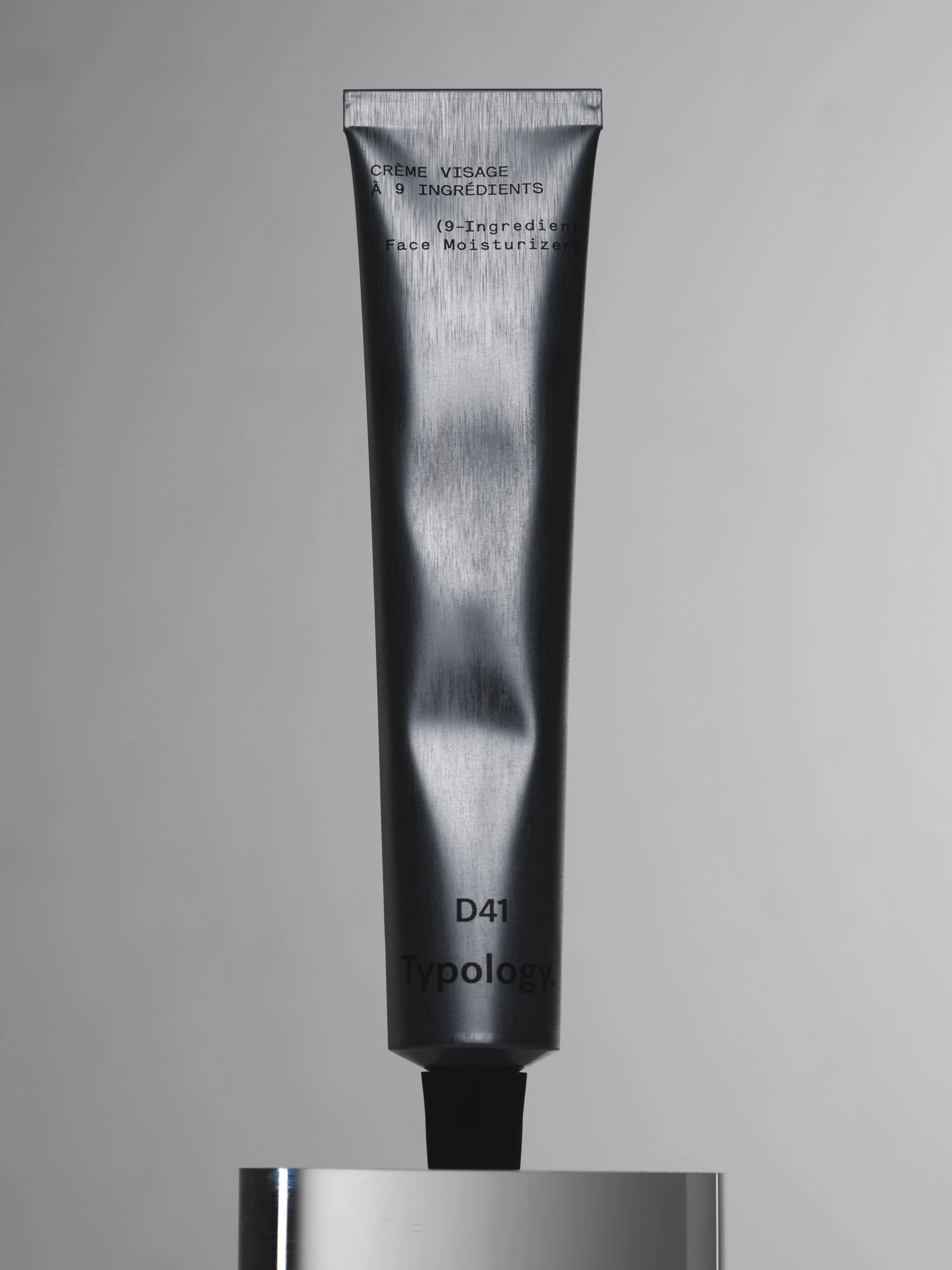 Tubul d'aluminium gris foncé avec des inscriptions noires, posé sur une surface métallique.