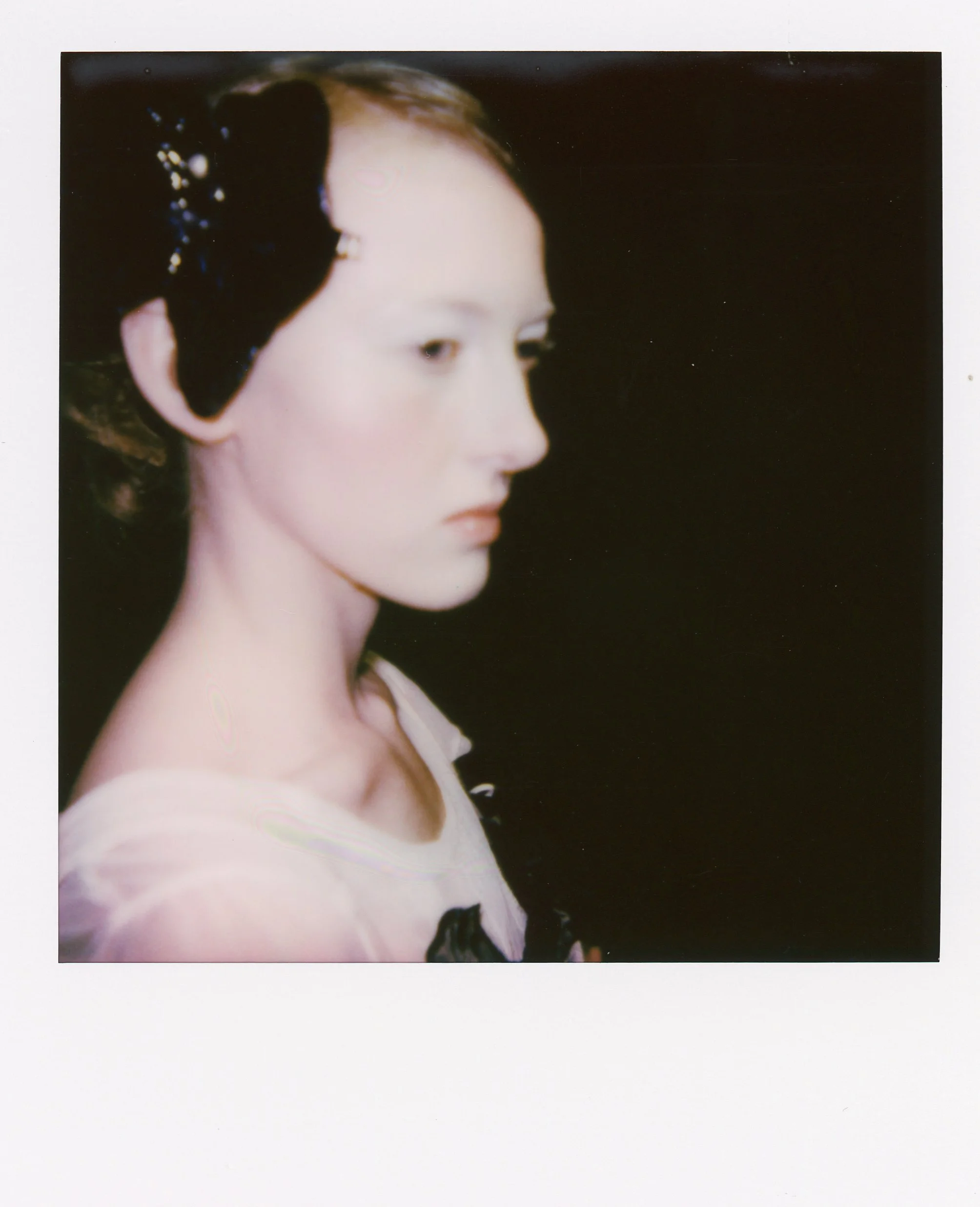 Portrait d'une femme avec une coiffure traditionnelle japonaise, portant un kimono clair, avec un fond noir.