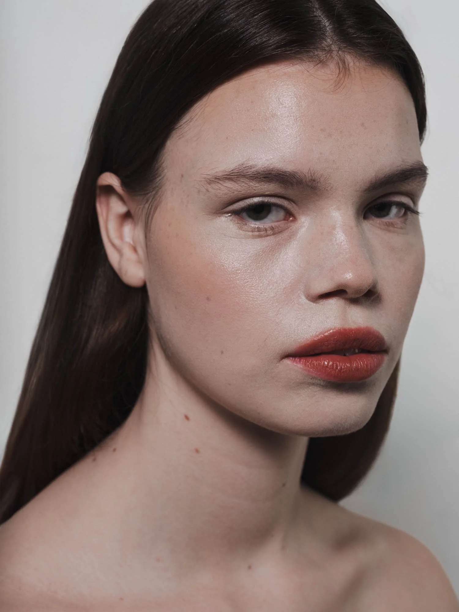 Portrait d'une jeune femme avec peau claire, cheveux bruns et lèvres oranges.