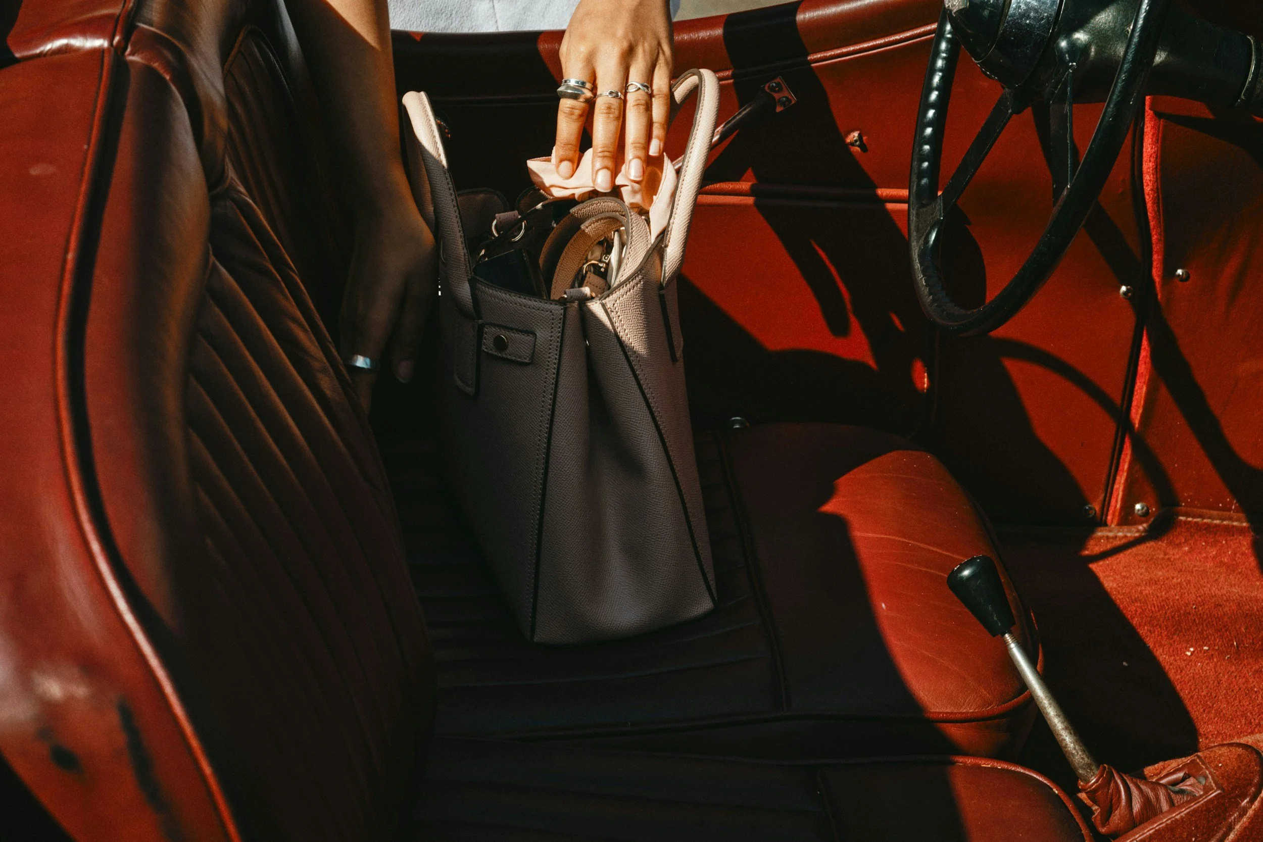 luxury leather bag place in a vintage convertible with red seats