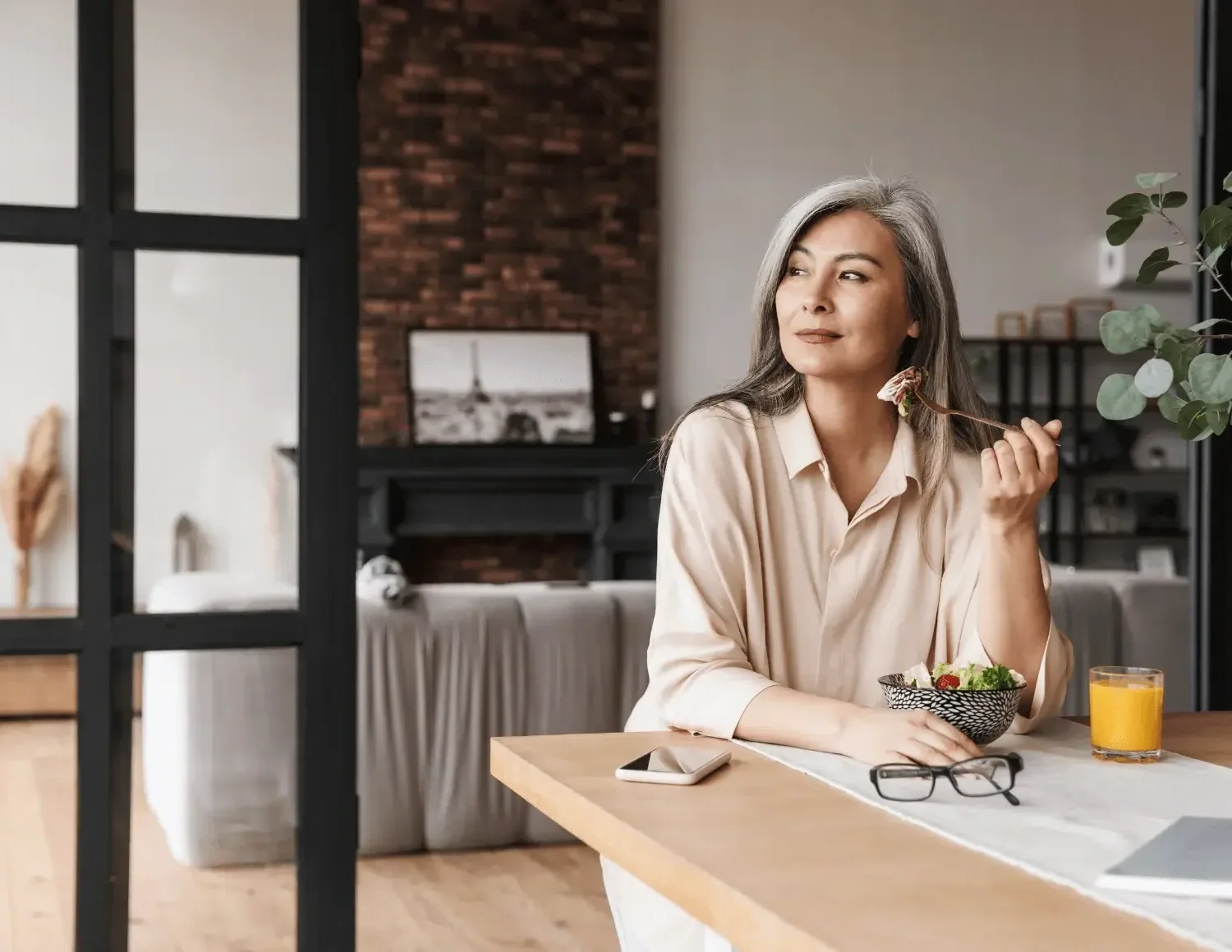 An older woman with gray hair sitting at a dining table after pelvic floor dysfunction at Zelena Medicine.