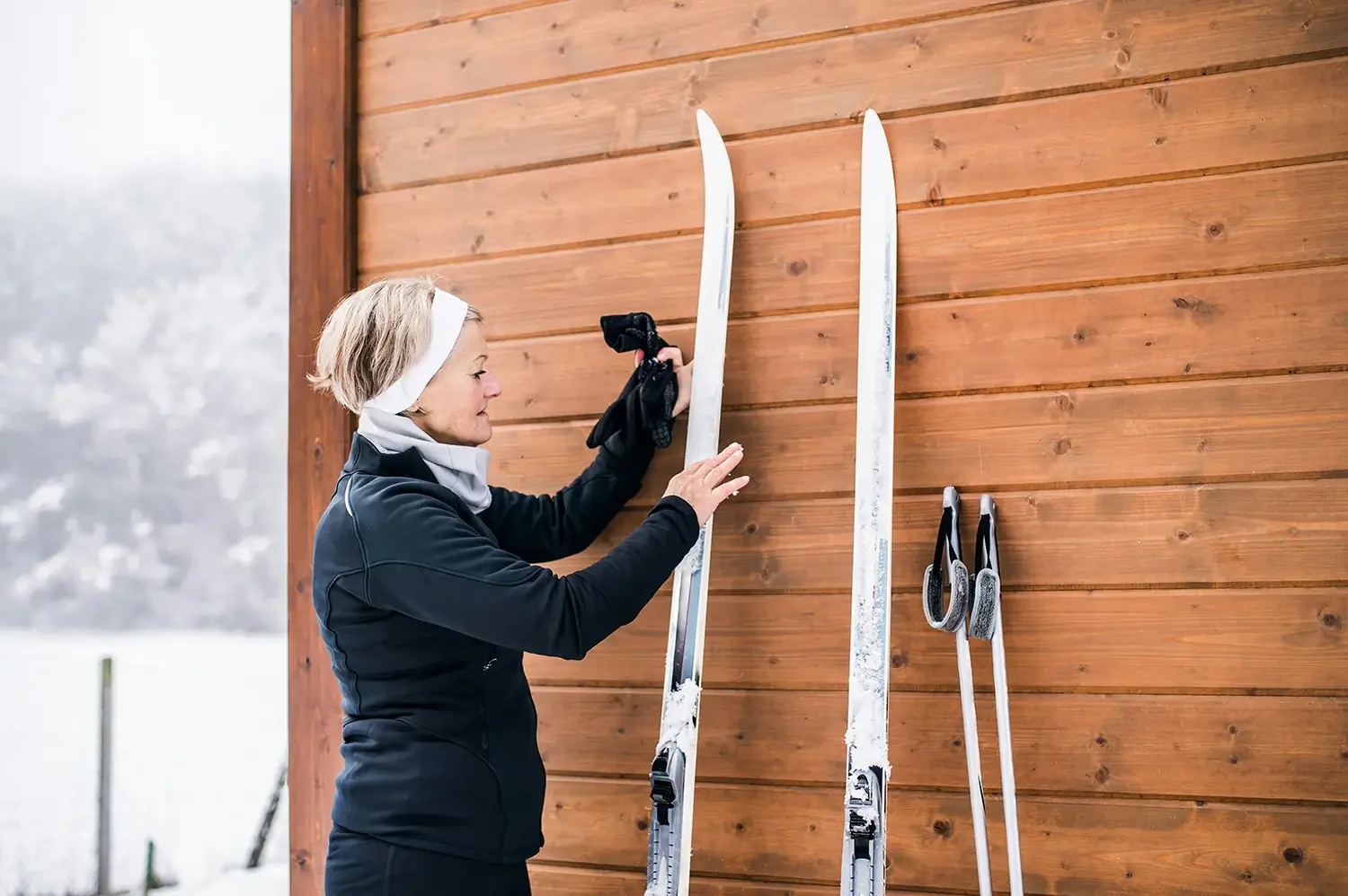 A woman dressed in black winter sports gear holding a pair of used skis after functional medicine appointment in Aspen.