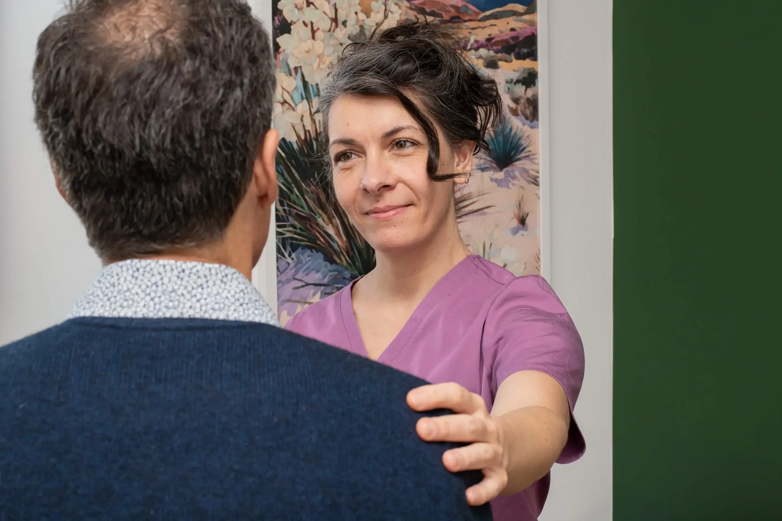 Mishe Skenderova, acupuncturist at Zelena Medicine in Basalt, Colorado places her hand on a man's shoulder during a comforting interaction.