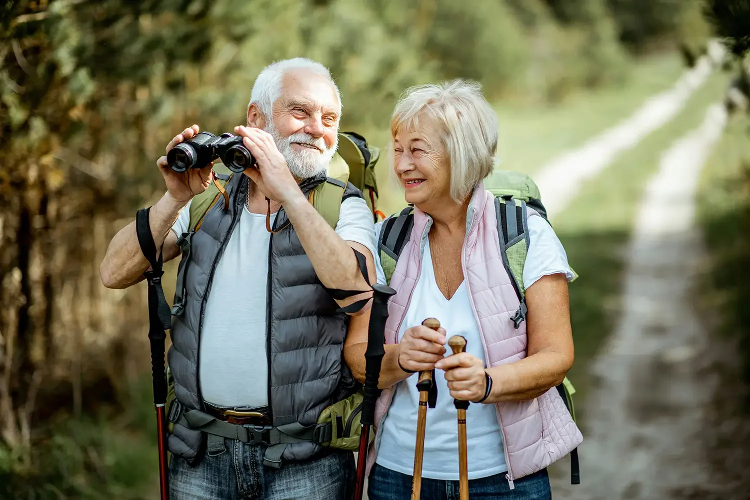 An elderly couple with backpacks enjoying a hike in Colorado after acupuncture.