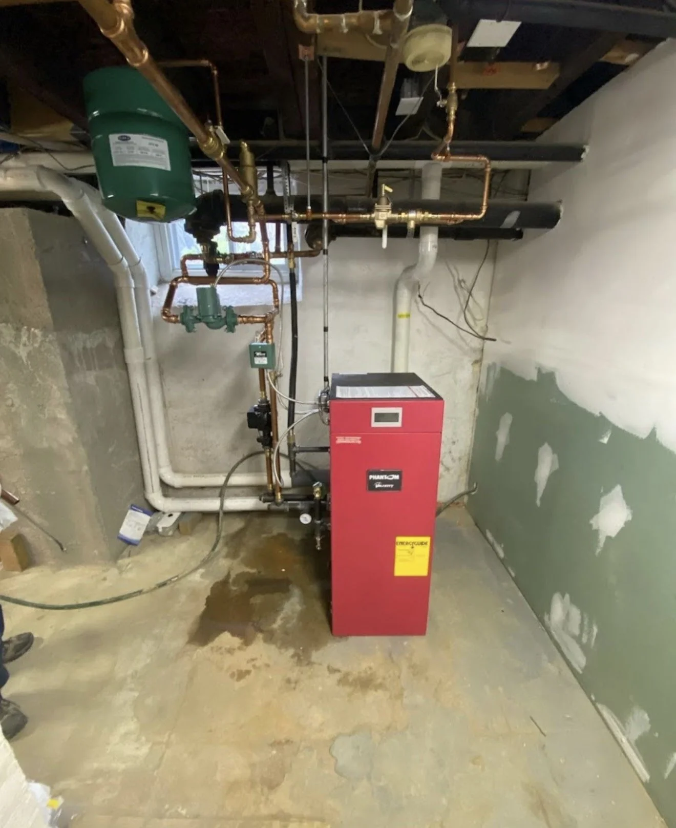 A utility room with a boiler system, copper pipes, and a red boiler unit.