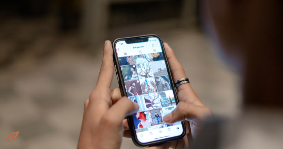 Bilde av en som holder en telefon med instagram feeder sin oppe. Start vestfold tin logo i venstre hjørne.