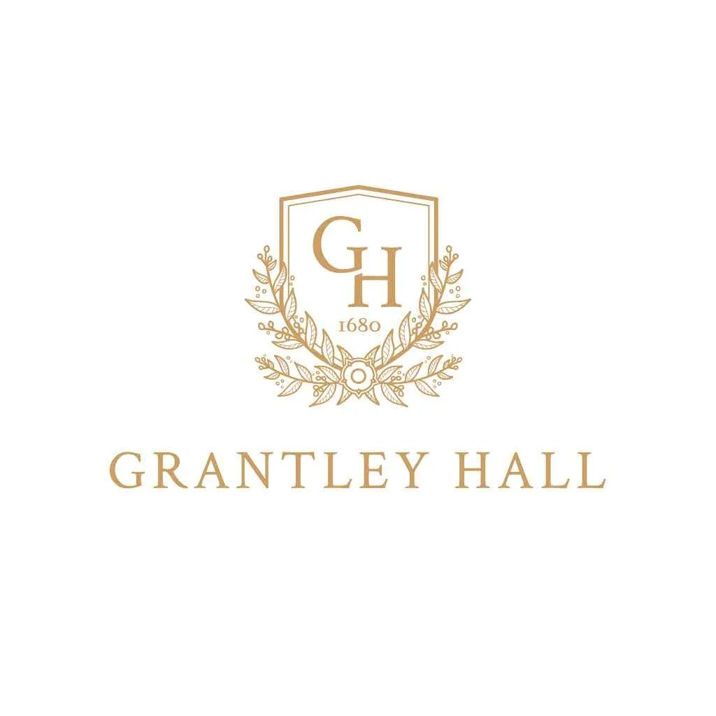 A logo for Grantley Hall featuring a hexagonal shape with the initials G and H, surrounded by laurel leaves, with the year 1680 and the text 'Grantley Hall' written below.