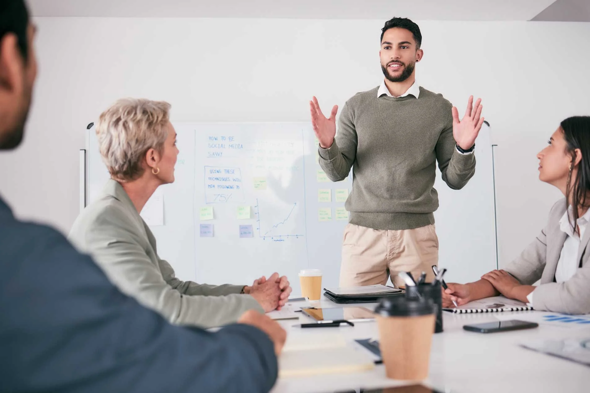 Young male project manager leading a team meeting in a modern office.