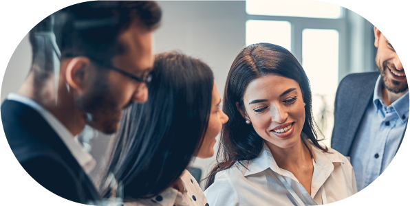 Office workers gathered around a desk, discussing a project and reviewing documents