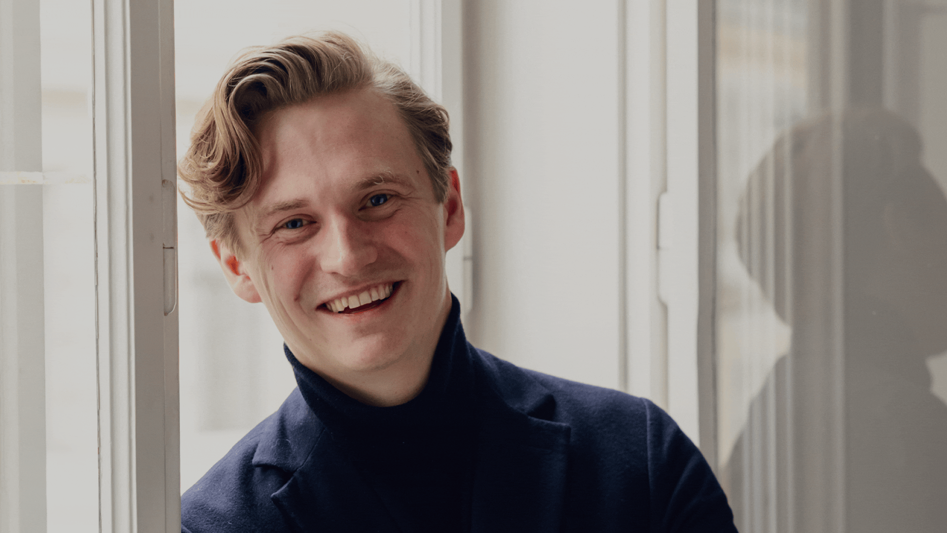 Three portraits of lawyer Dominik Loidl smiling in a dark blue suit.