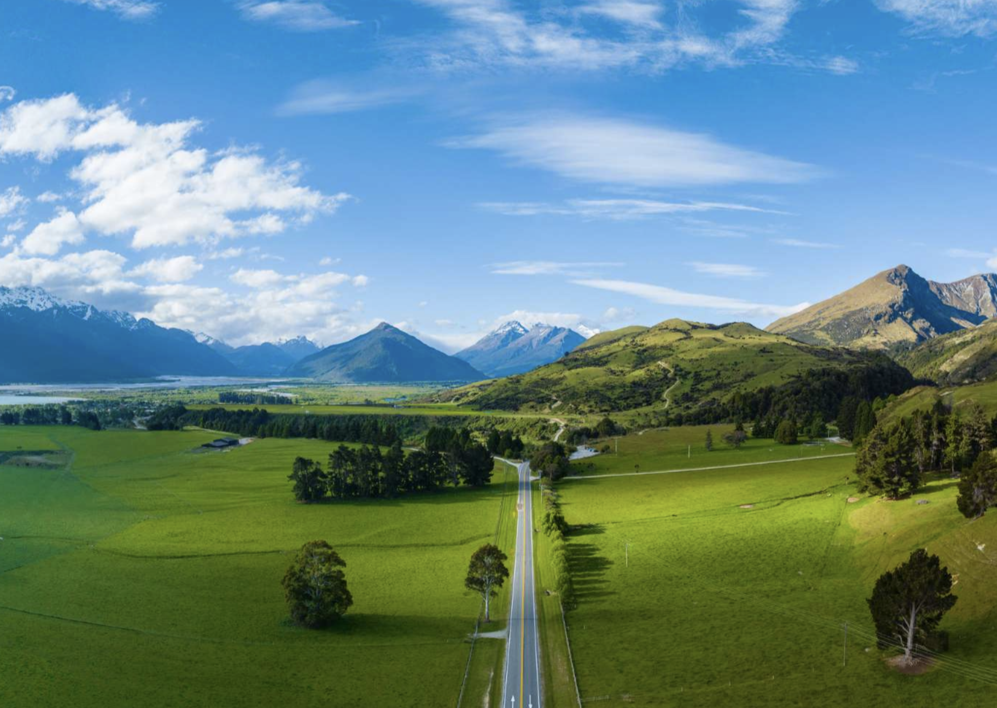 New Zealand countryside landscape featured on a Studio One Yoga & Fit4travel retreat, with a road leading toward snow-capped mountains.
