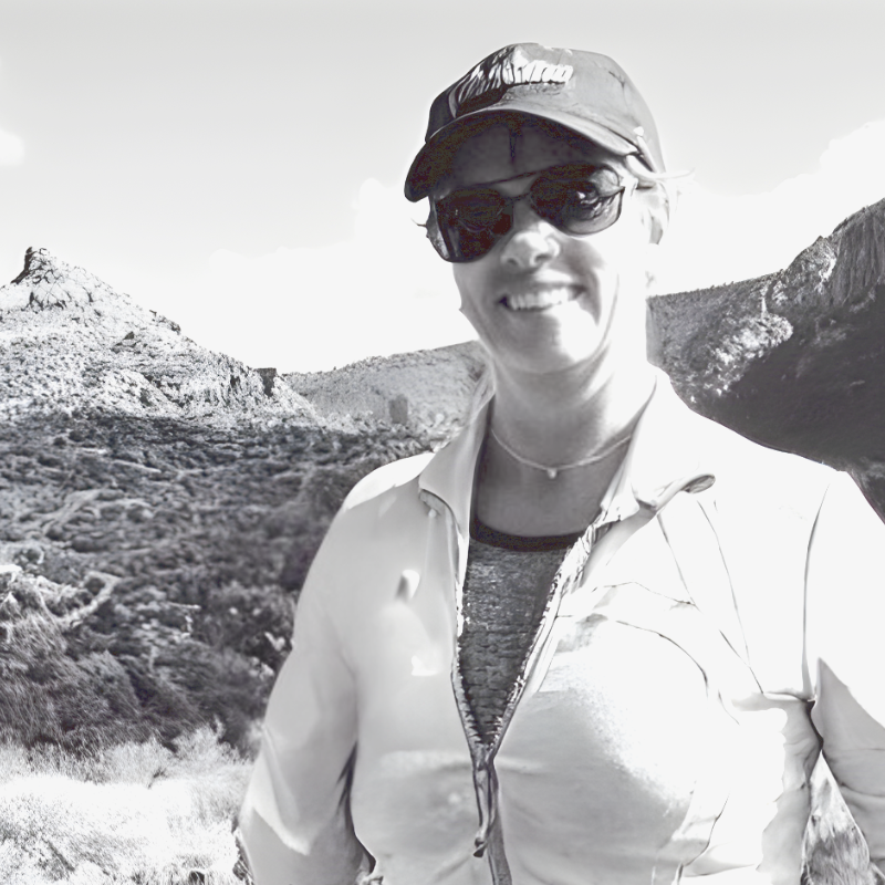 A man with gray hair sitting on the edge of a beige cushioned bench against a beige wall, casting a shadow to his right.