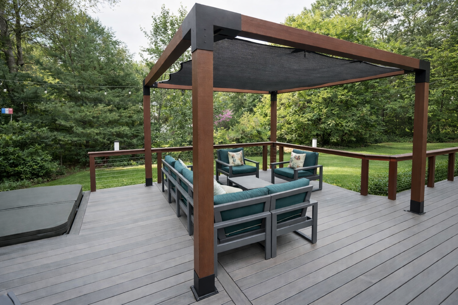 Outdoor deck with seating area under a pergola, surrounded by trees and grass.