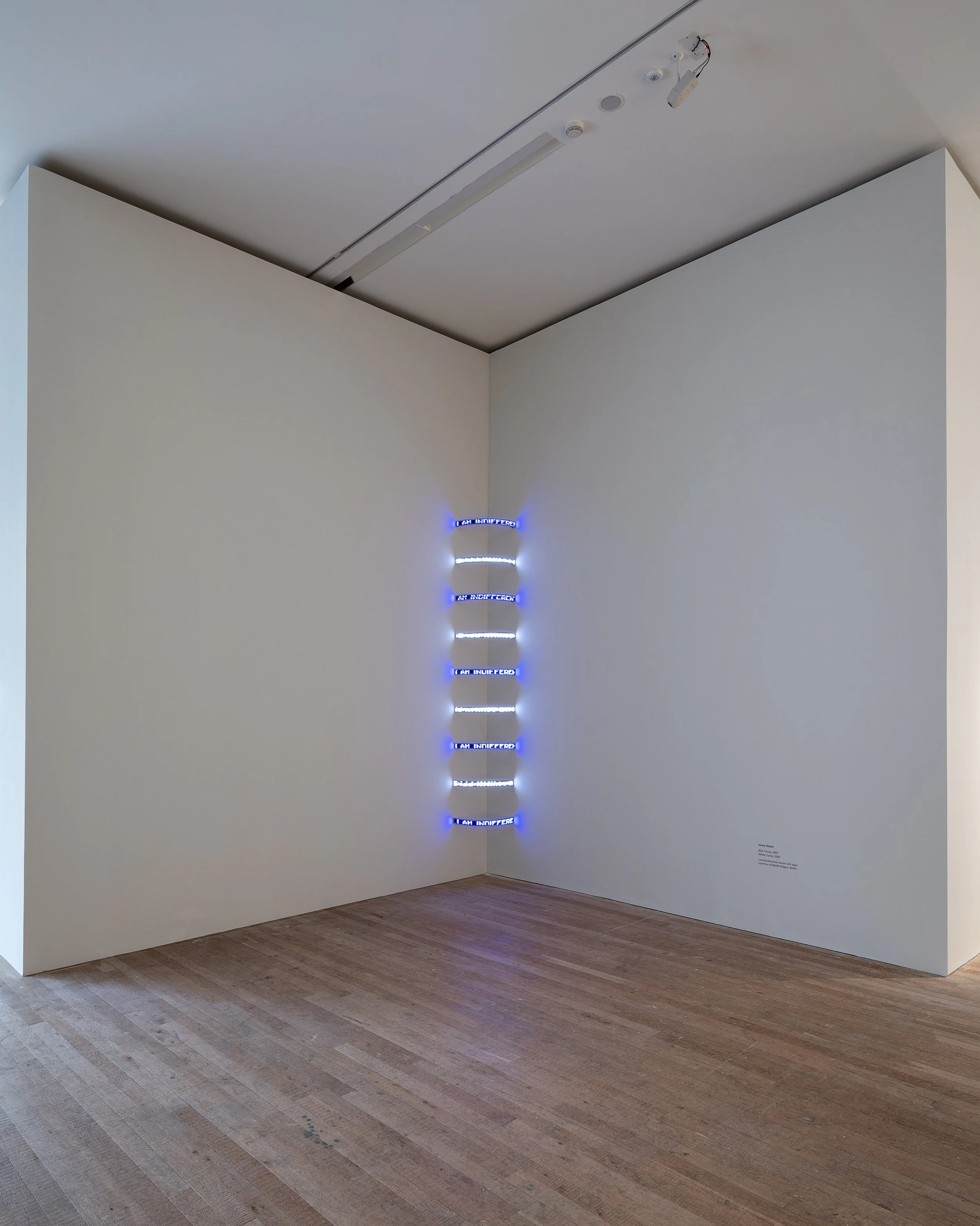 Contemporary art installation with illuminated horizontal strips on a white corner wall in a gallery.