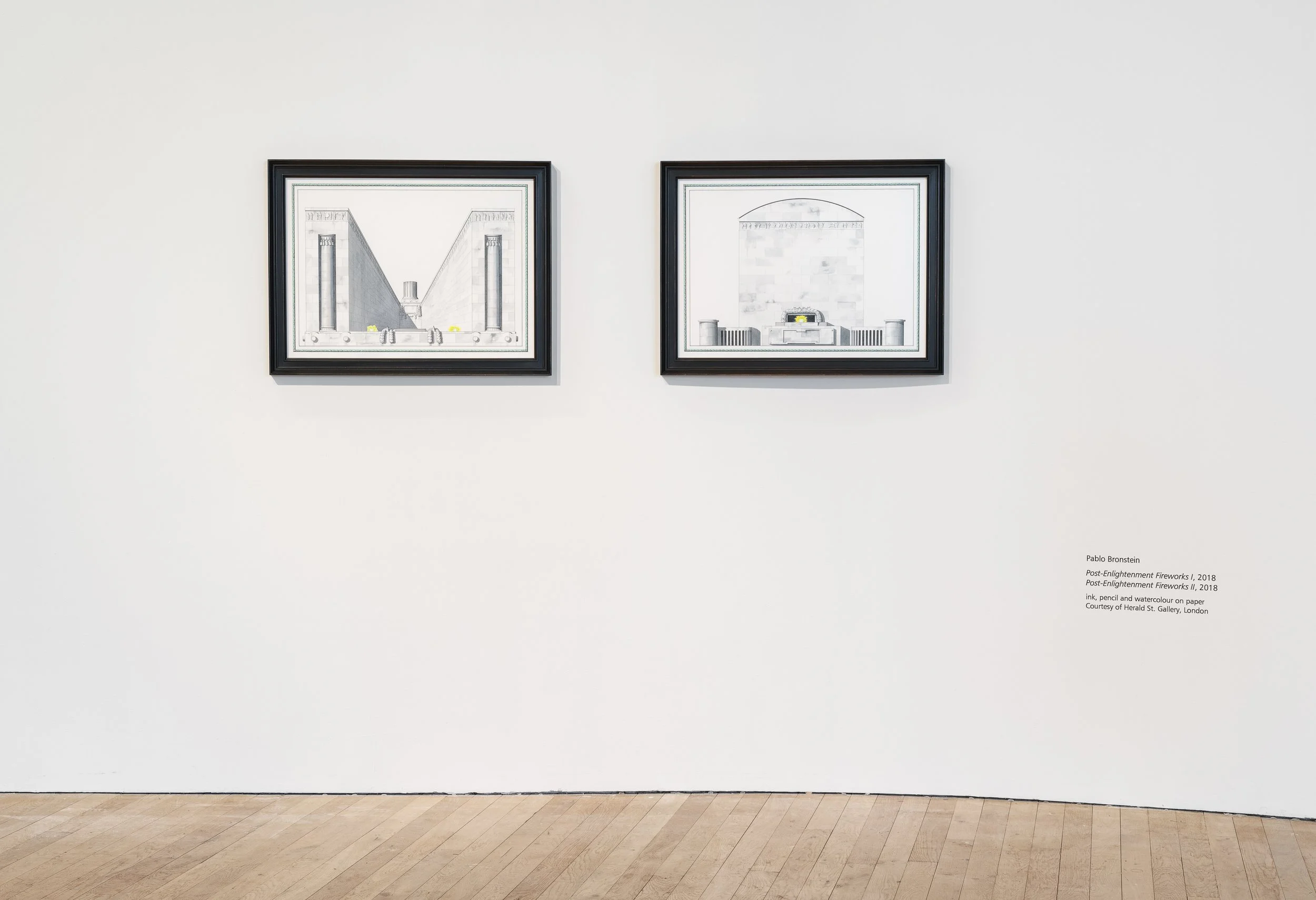 Two framed art pieces hanging on a white gallery wall, with a description of artist Pablo Bronstein's work titled 'Post-Enlightenment Fireworks I, 2018'.