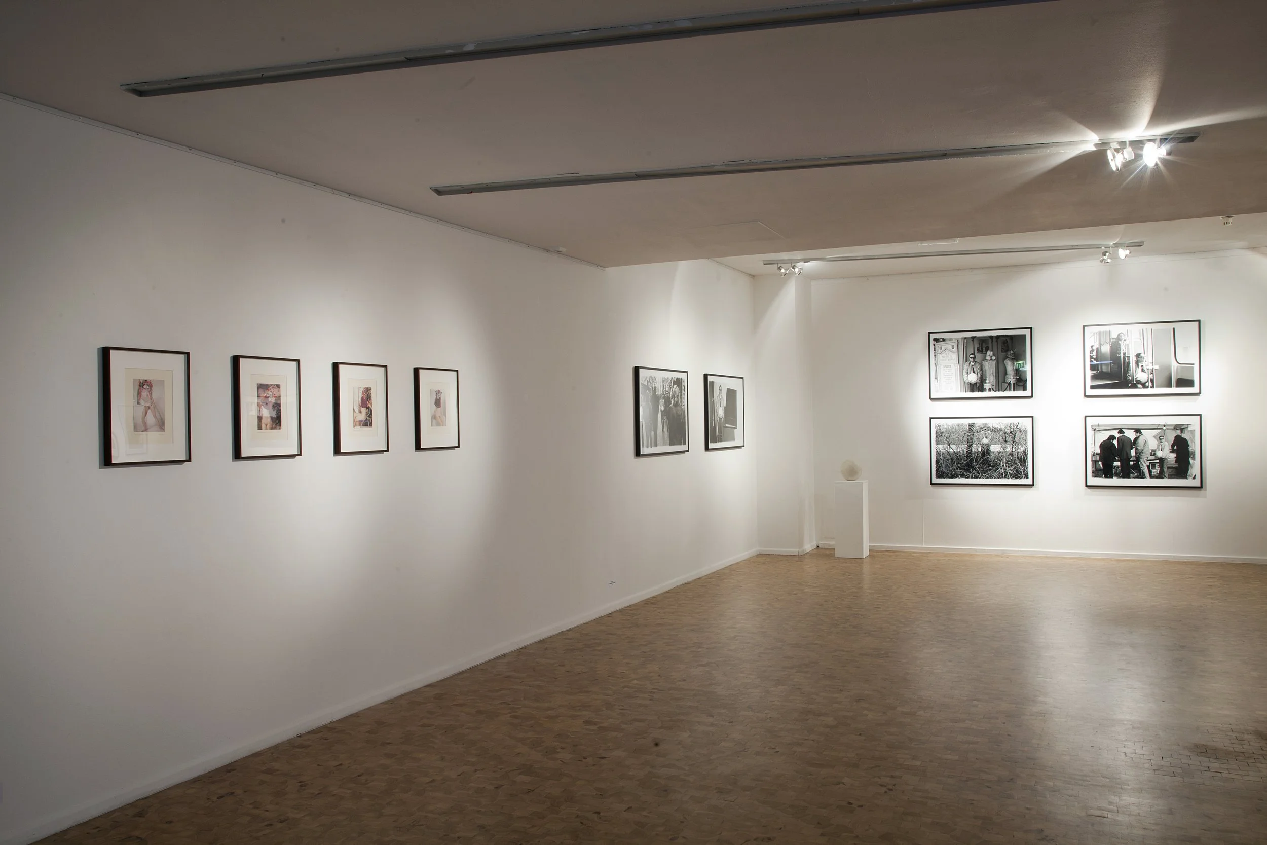 An art gallery with framed photographs displayed on white walls and hardwood floors.