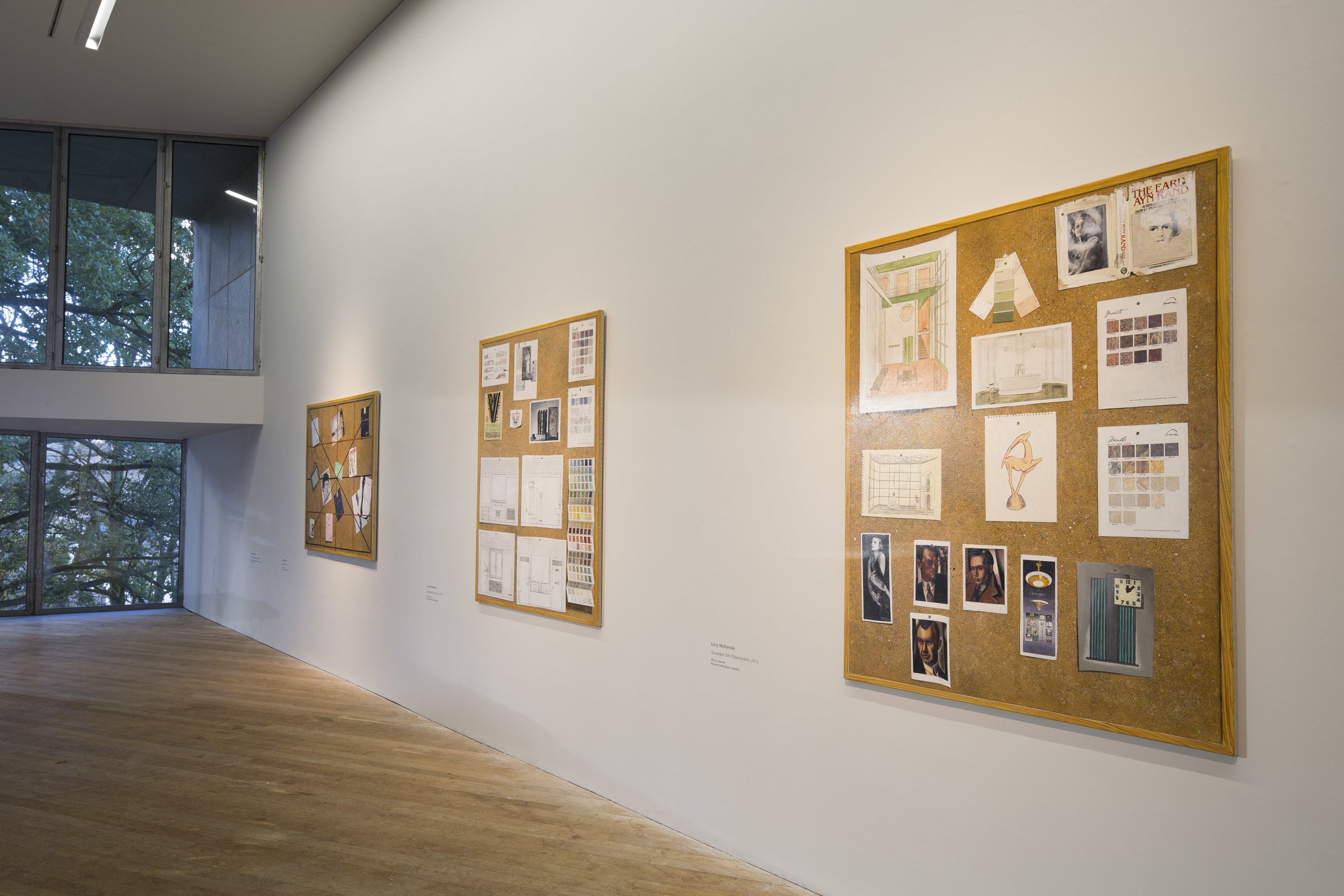 Gallery wall with three paintings of bulletin boards displaying various sketches, images, and notes in an art museum, with large windows in the background revealing tree branches outside.