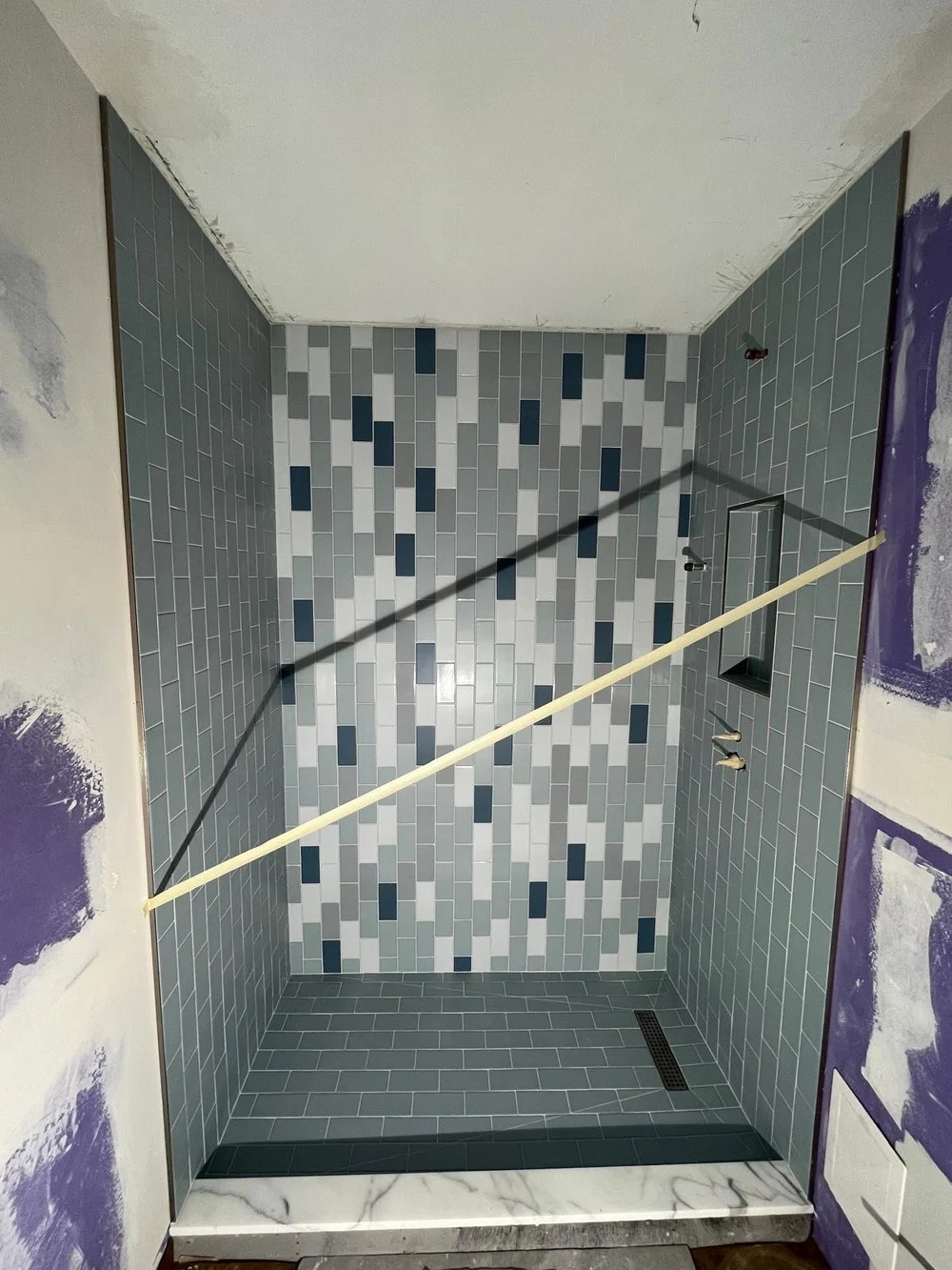 New blue and white shower tile being installed