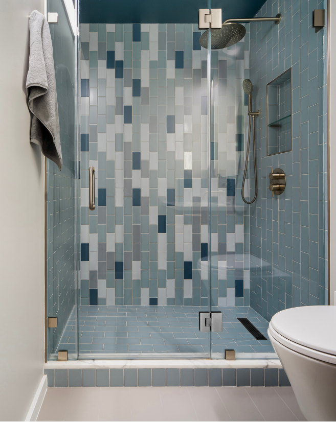 Blue and white tiled walk-in shower with brass fixtures