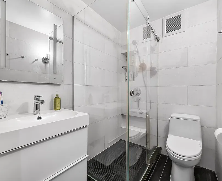 Loft bath before: white vanity, glass shower and dark floor tile